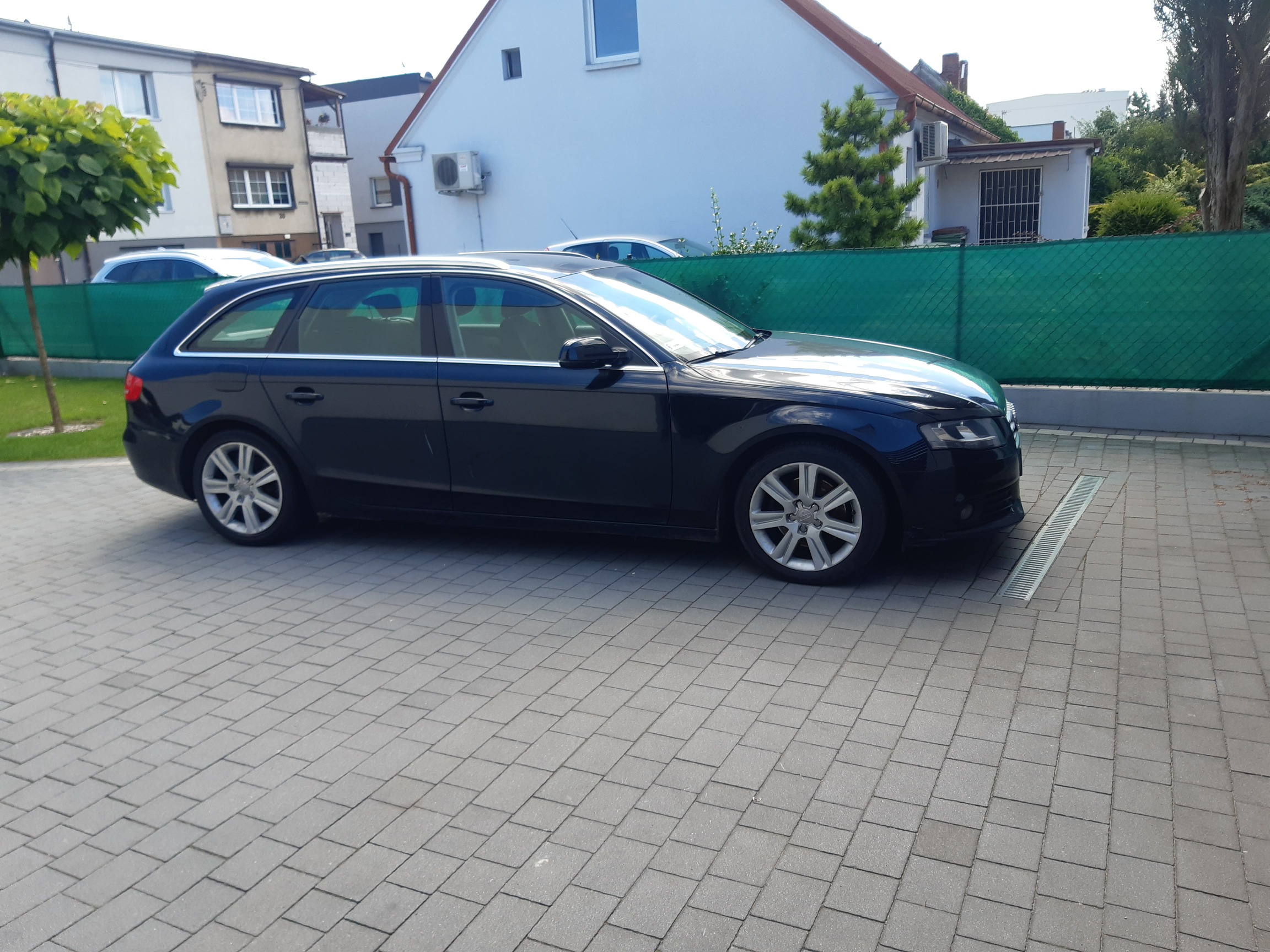 Czarny samochód Audi A4 B8 w nadwoziu kombi, pokazany z boku. Widoczna linia dachu z relingami i aluminiowe felgi.