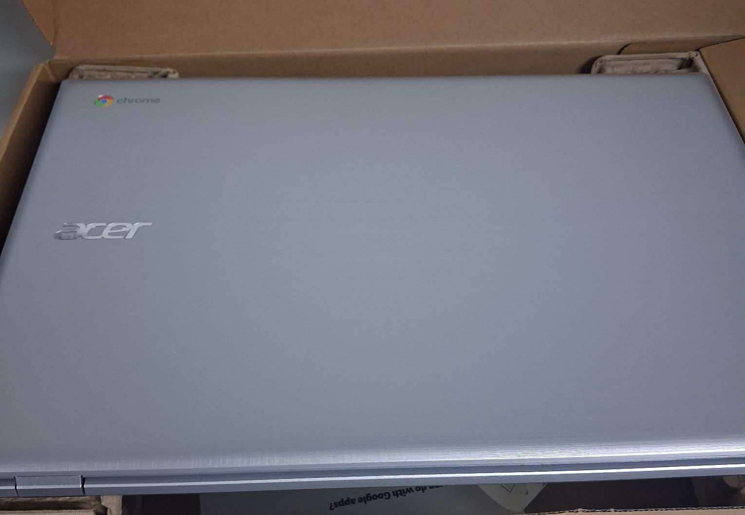 Laptop koloru srebrnego z napisem Acer w opakowaniu kartonowym koloru brązowego.