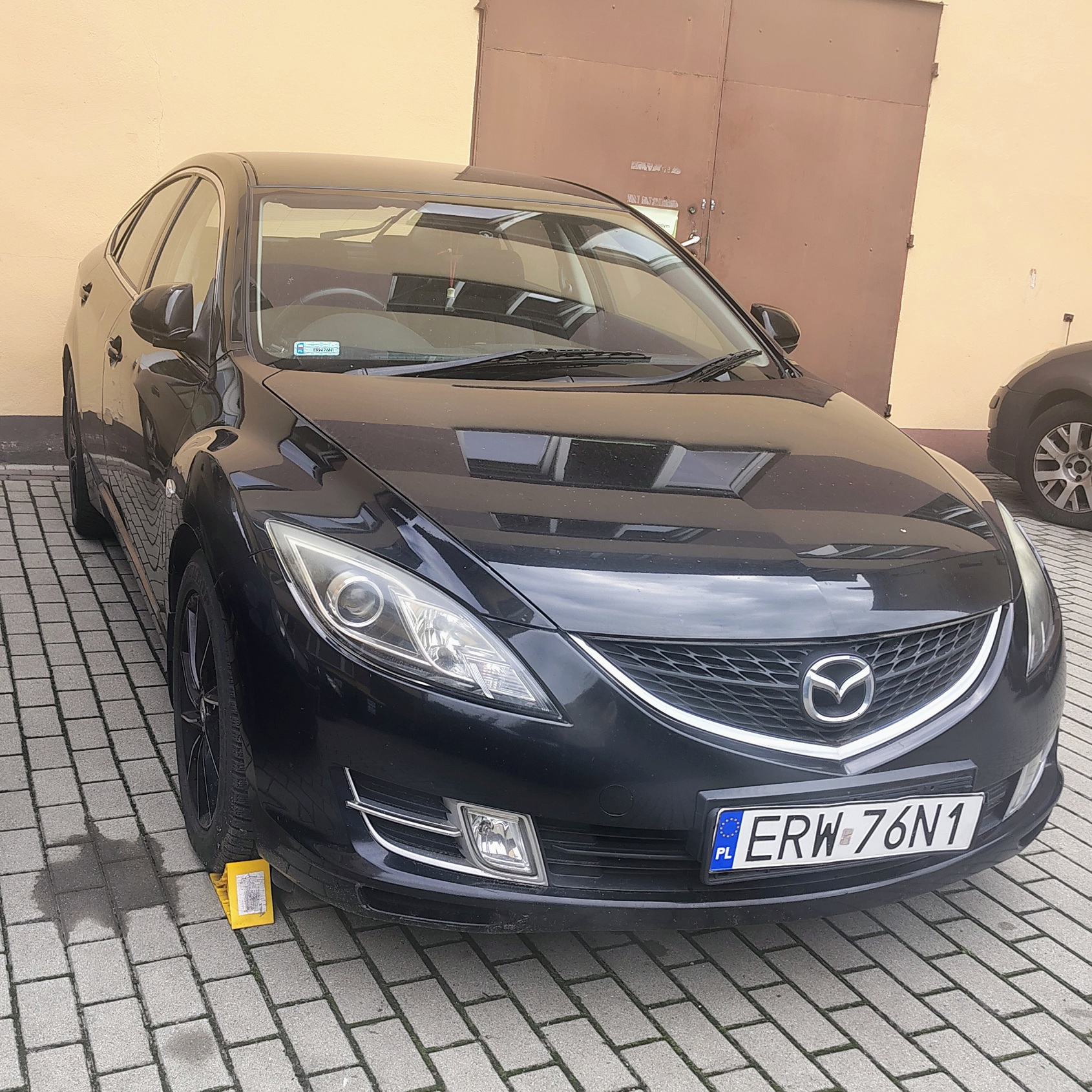 Czarny samochód osobowy marki Mazda typu hatchback. Reflektory mają nowoczesny kształt a grill zdobi chromowana listwa.
