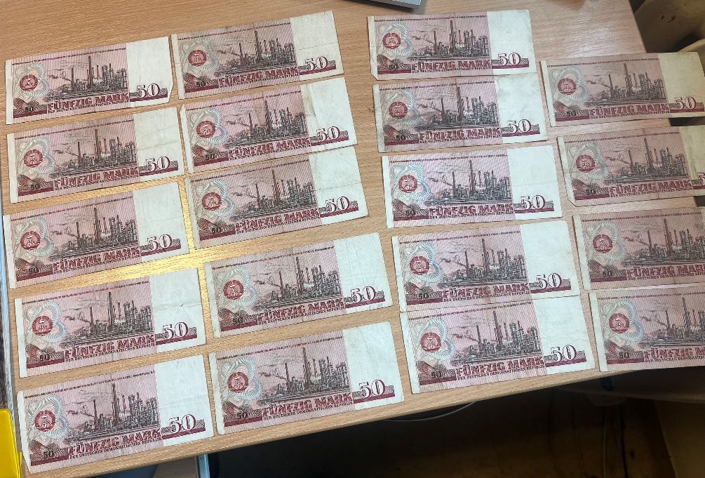 Rewersy banknotów o nominale 50 marek NRD ułożonych w kilku rzędach.