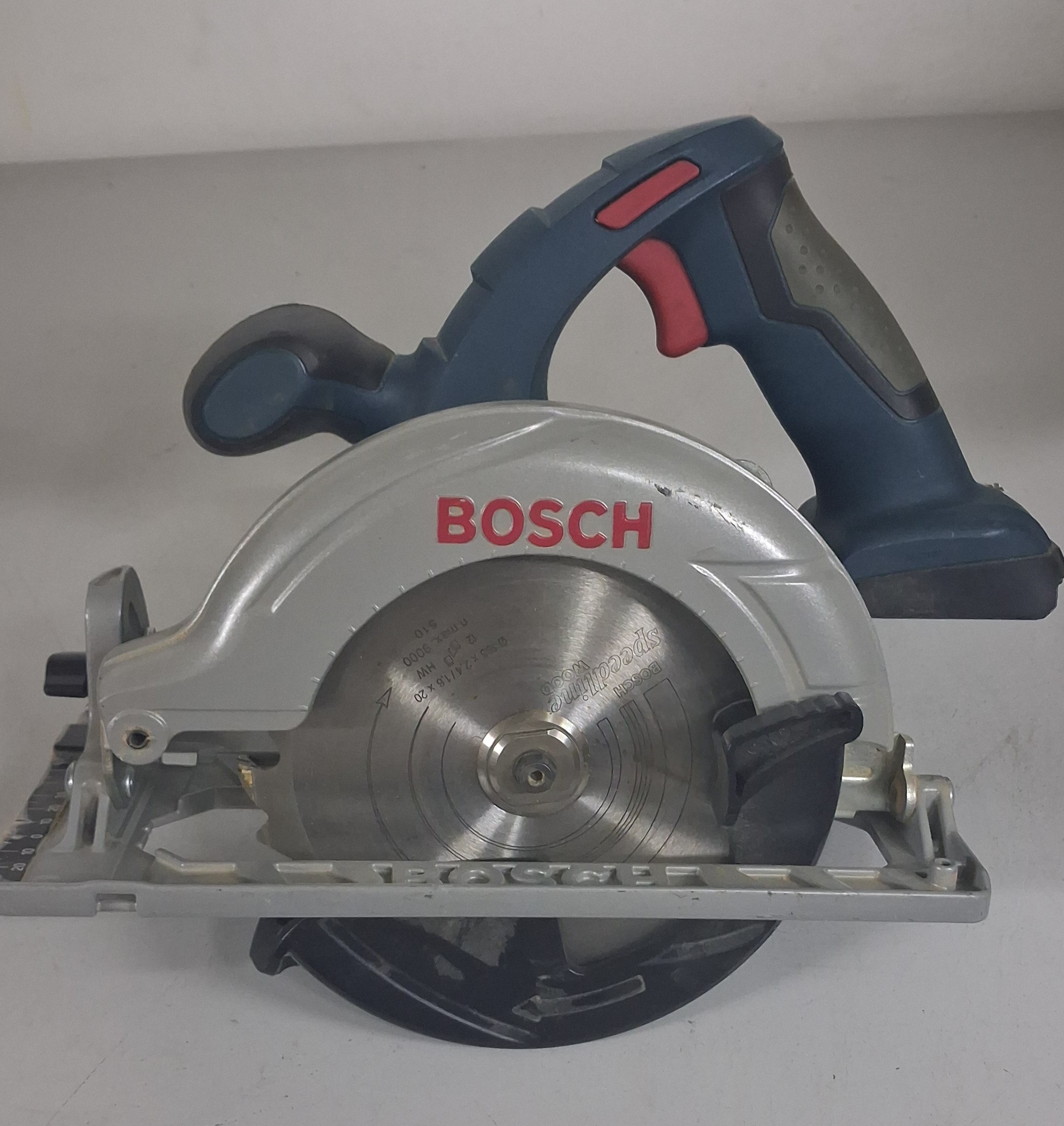 Ręczna piła ze srebrną tarczą tnącą, srebrną i czarną obudową z napisem BOSCH, rękojeść z czerwonym włącznikiem.