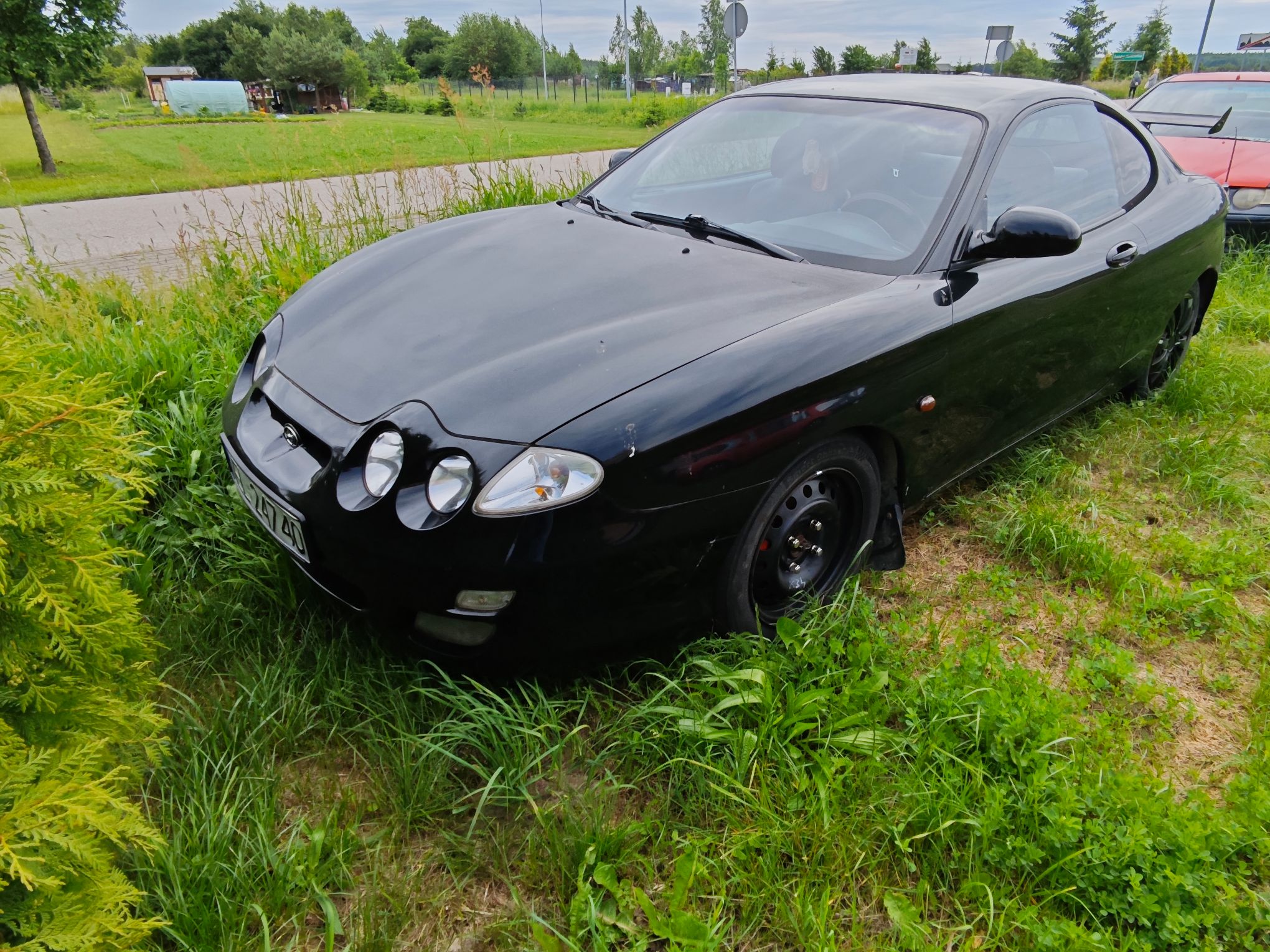 Czarny dwudrzwiowy Hyundai coupe, widoczne drobne ślady użytkowania na karoserii.