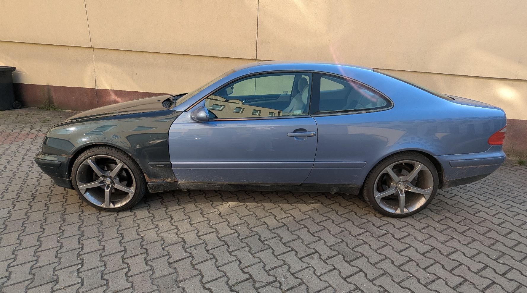 Lewa strona samochodu Mercedes-Benz CLK 200. Przednie nadkole w kolorze ciemnozielonym z oznakami korozji.
