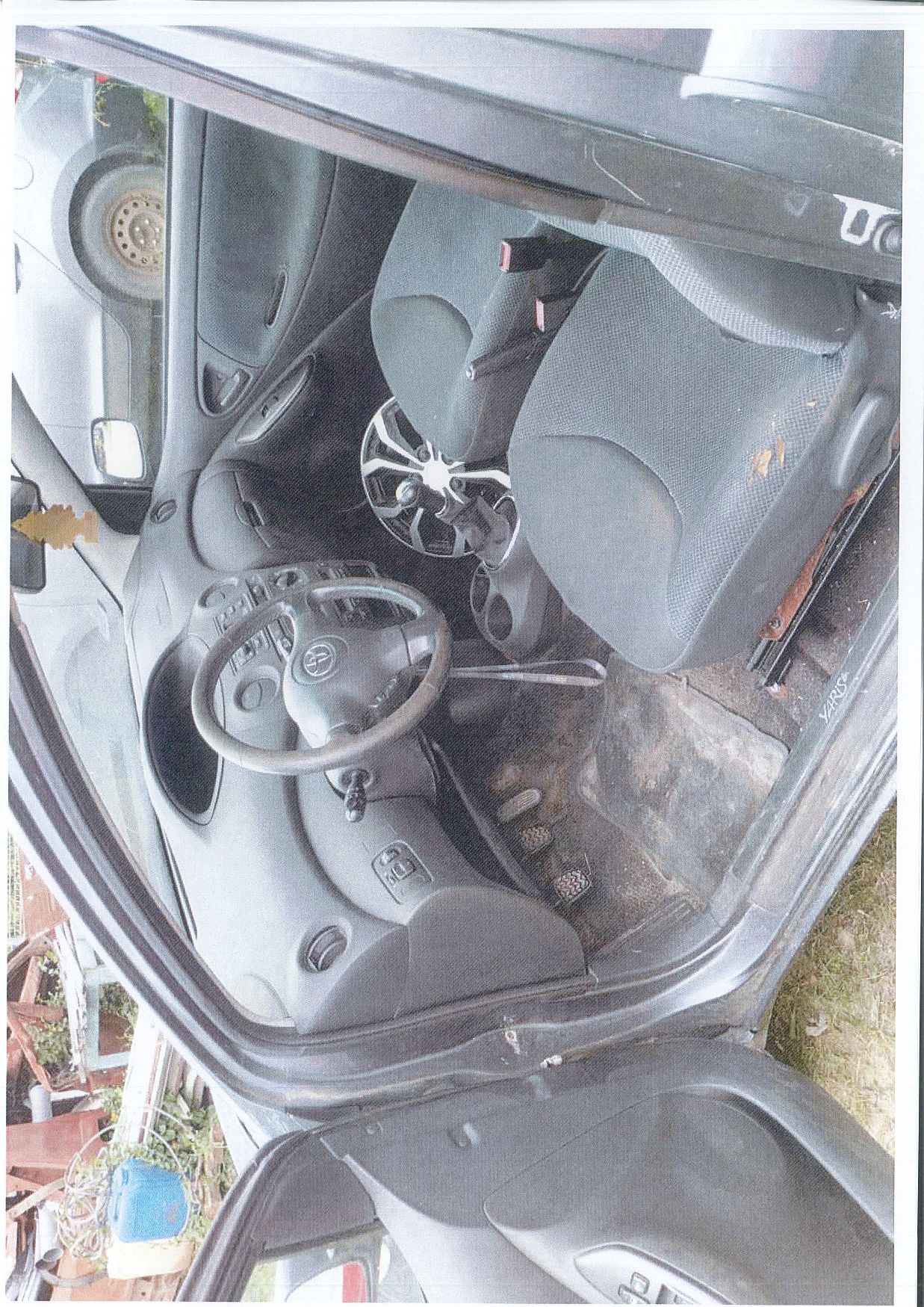 Wnętrze samochodu osobowego TOYOTA YARIS, przód. Tapicerka fotela kierowcy uszkodzona i mocno zabrudzona.