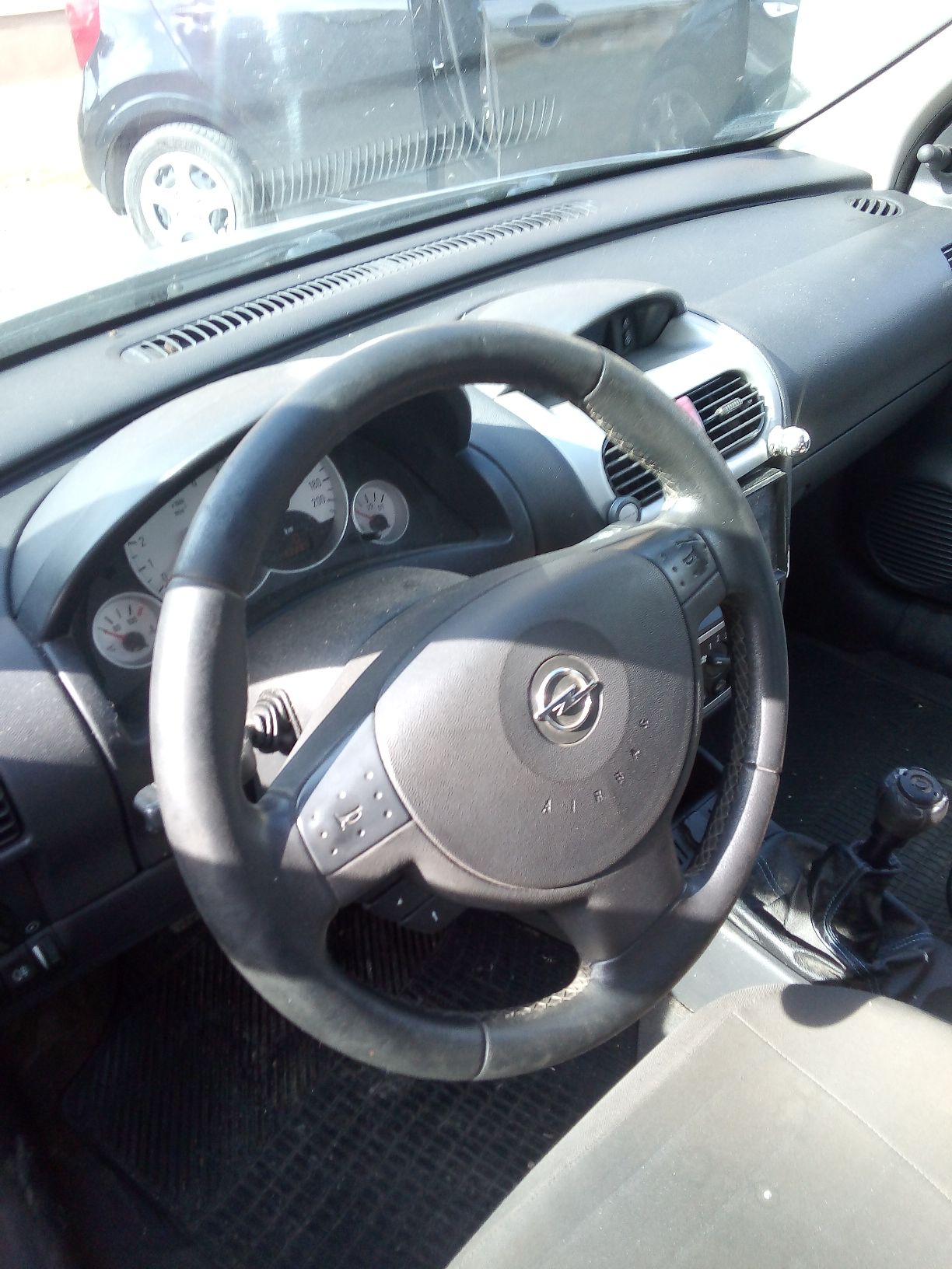 Wnętrze srebrnego samochodu osobowego marki Opel Corsa widziane od strony kierowcy