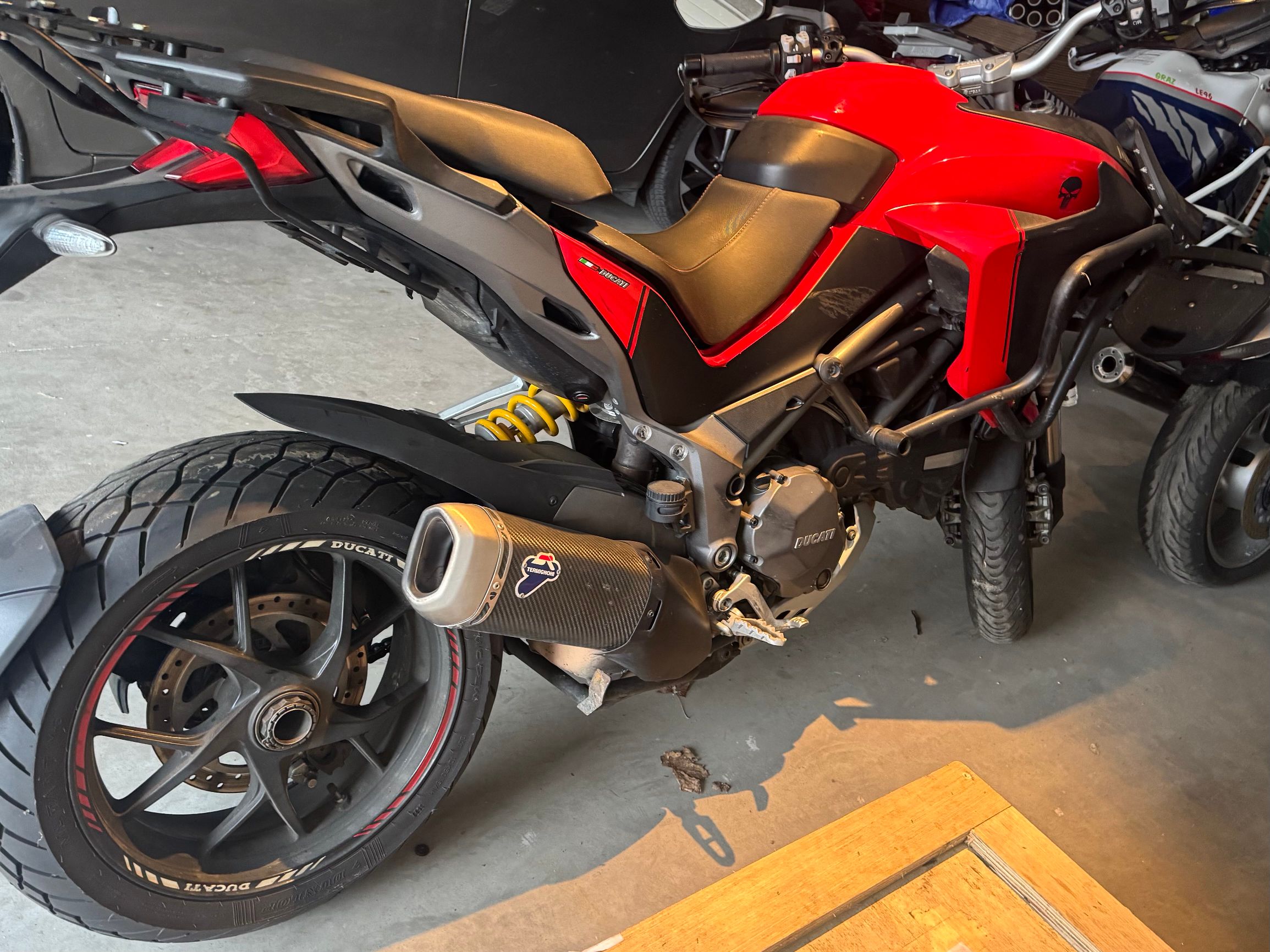 Tył czerwonego Ducati Multistrada. Motocykl stojący w garażu.