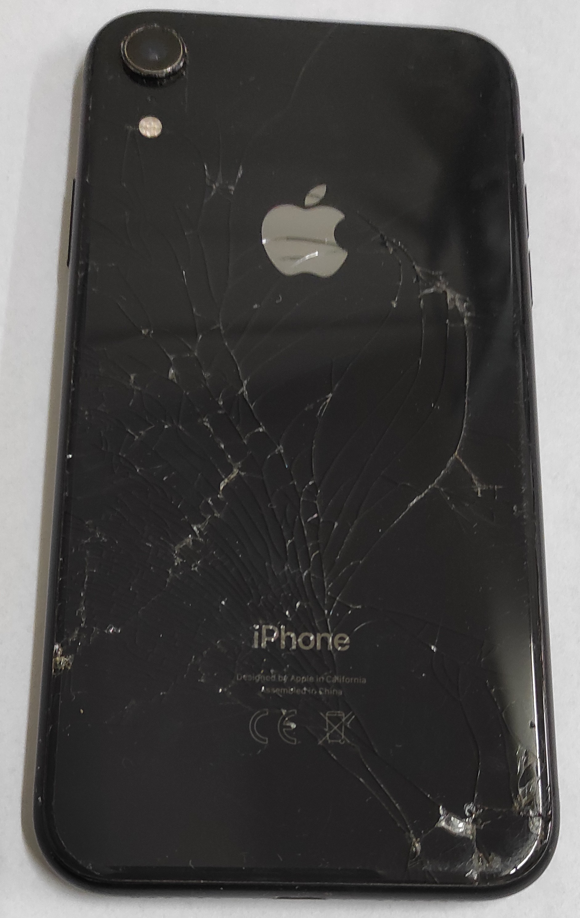 Popękana tylna obudowa koloru czarnego telefonu iPhone XR.