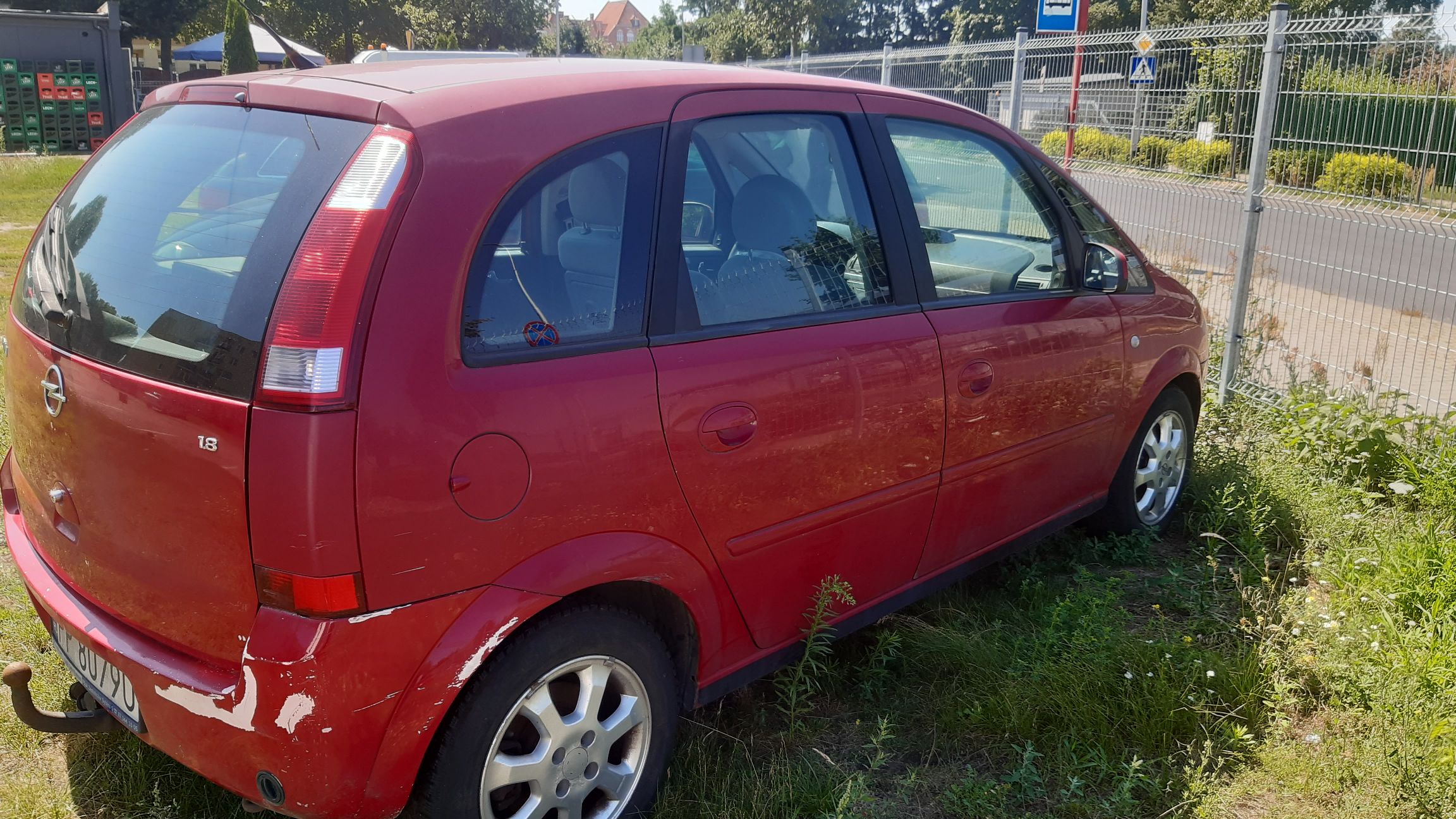 Czerwony minivan z uszkodzeniami lakieru na prawym tylnym błotniku i tylnym zderzaku
