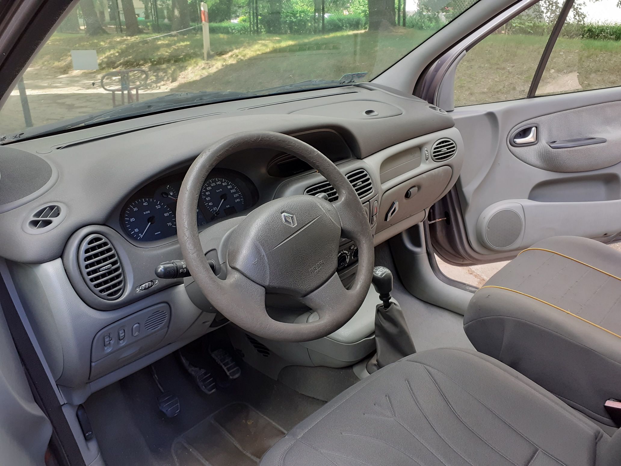 Wnętrze samochodu Renault Scenic z zaokrągloną deską rozdzielczą, kierownica z logo Renault, manualna skrzynia biegów.