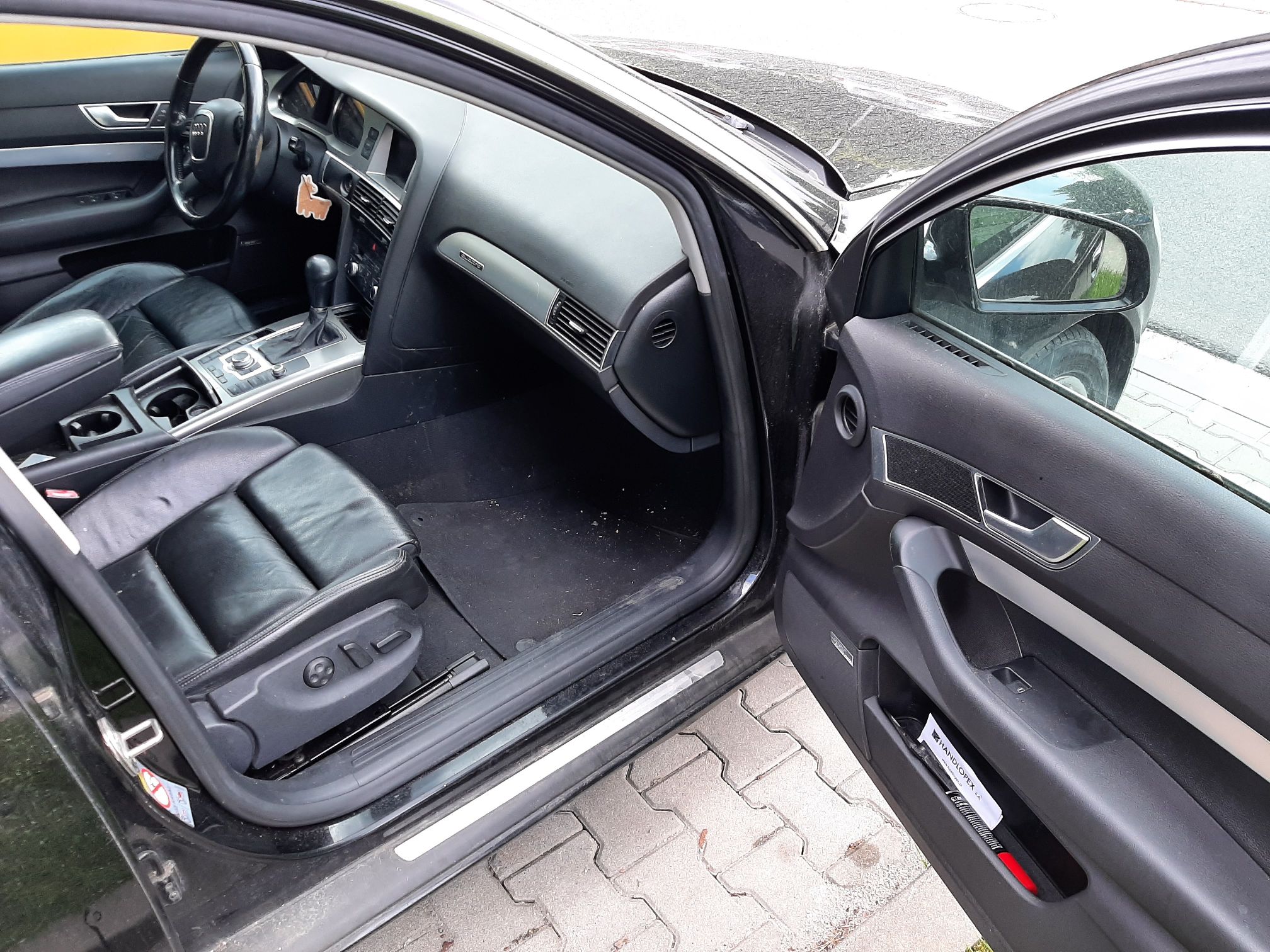 Wnętrze Audi z prawym fotelem z czarnej skóry, widoczna skórzana tapicerka, w głębi kierownica, deska rozdzielcza i konsola