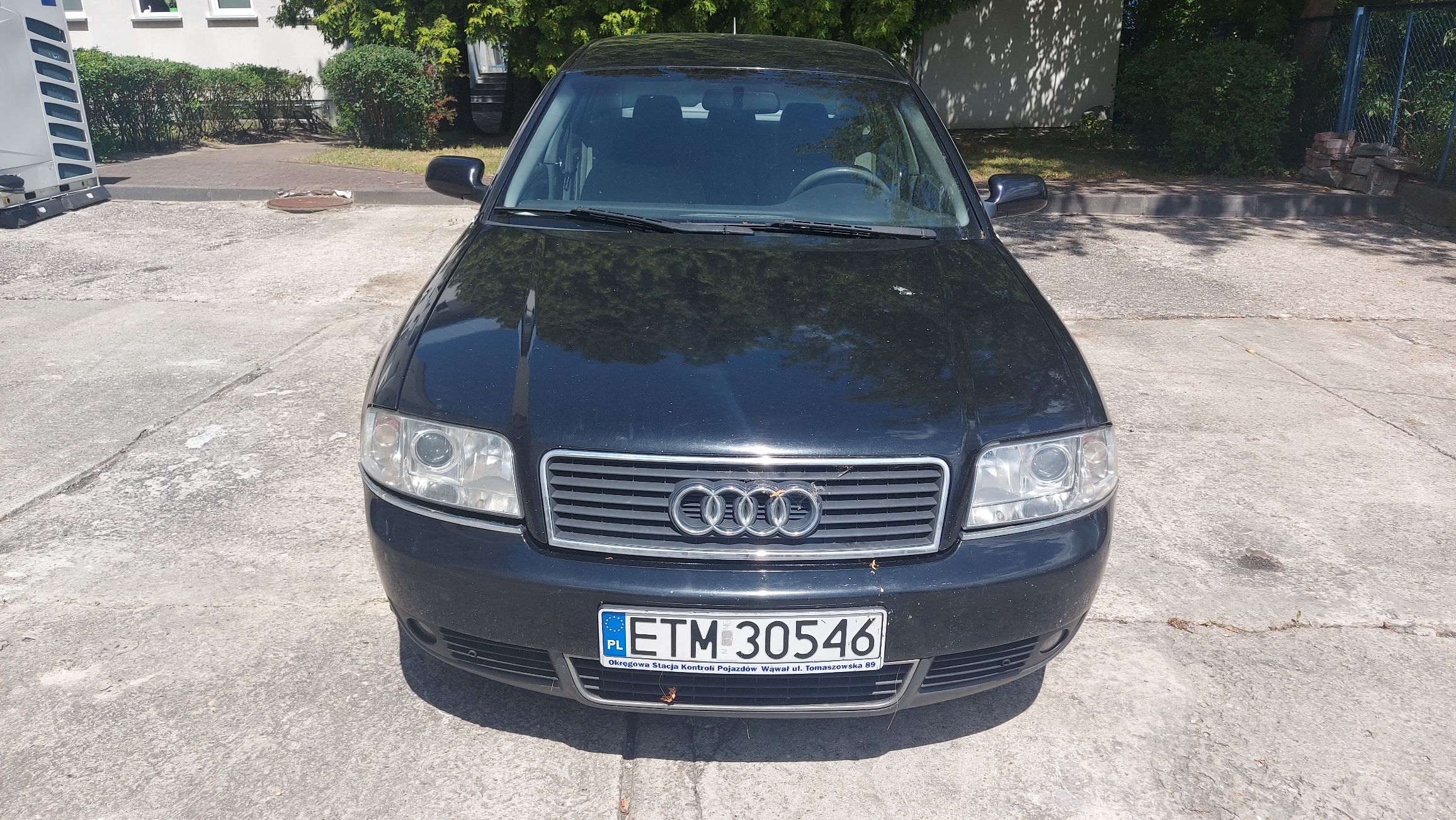 Przód czarnego Audi A6 C5. Widoczna przednia atrapa chłodnicy z logo marki, reflektory oraz tablica rejestracyjna ETM 30546.