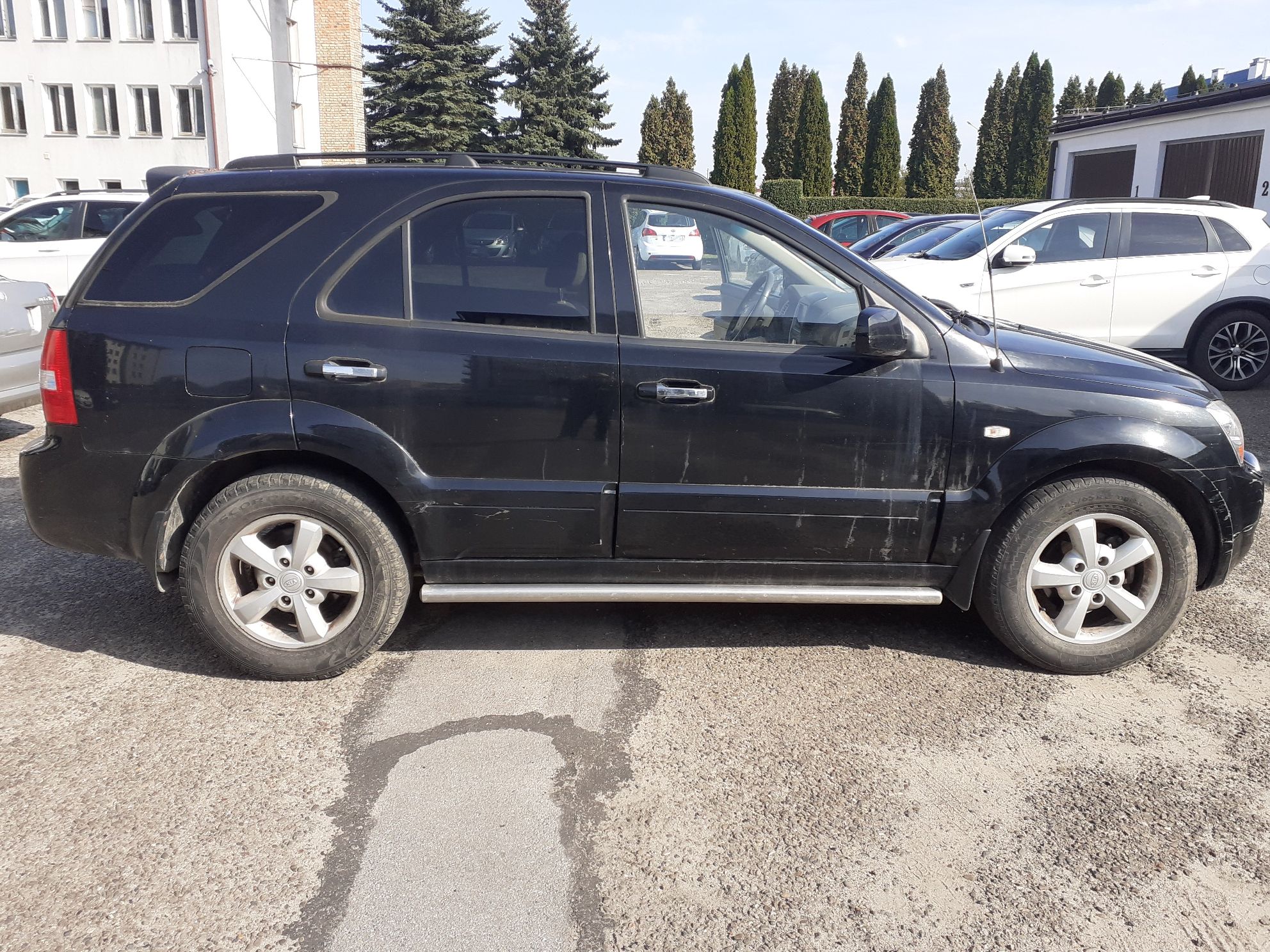 Czarny SUV Kia Sorento widok od strony pasażera. Widoczne srebrne progi boczne i pięcioramienne felgi aluminiowe.
