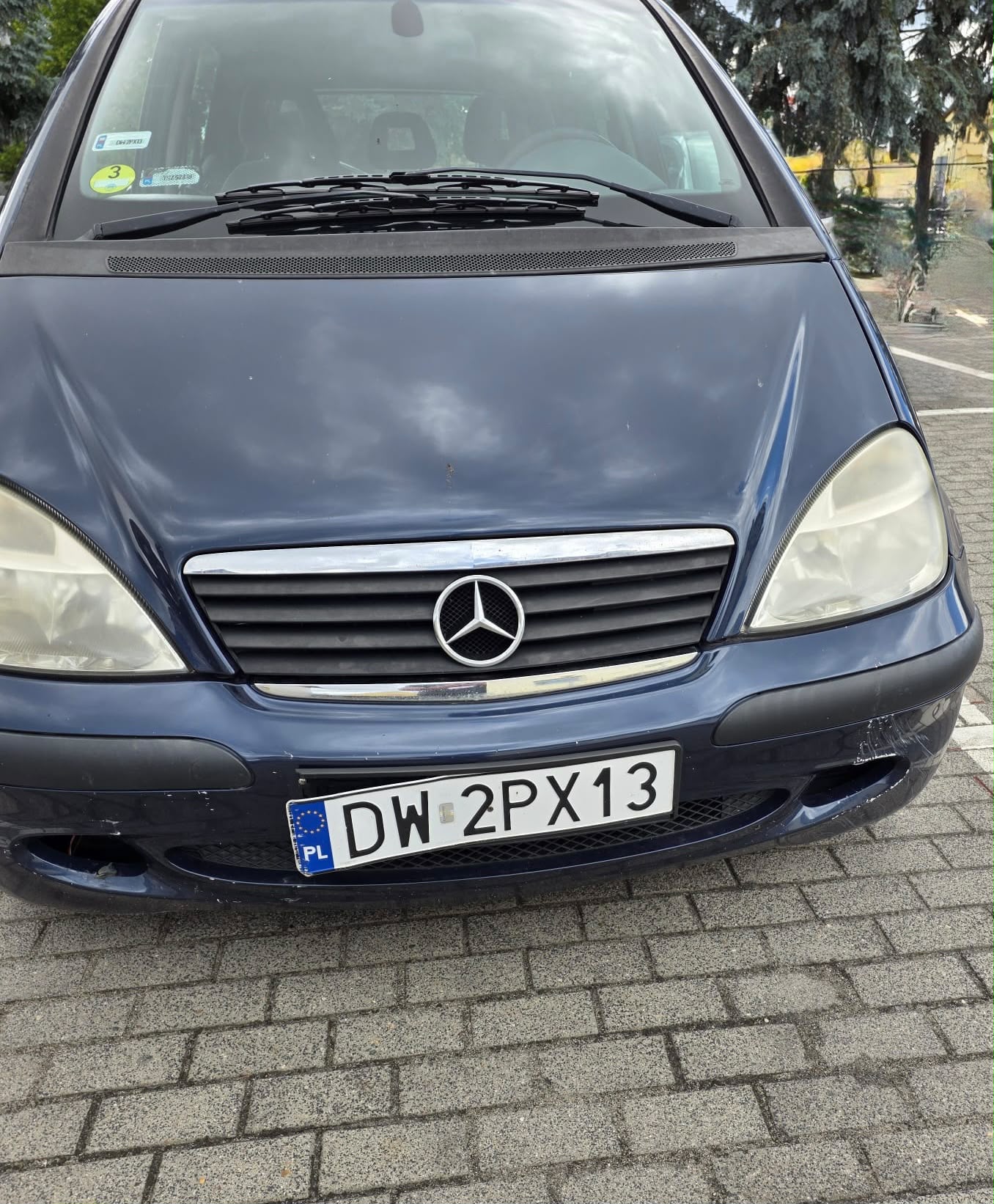 Mercedes-Benz w kolorze granatowym, widok z przodu, z widoczną i uszkodzoną tablicą rejestracyjną.