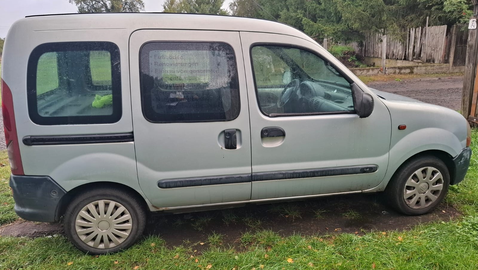 Prawy bok szarego Renault Kangoo z widocznymi oznakami korozji na prgu pojazdu