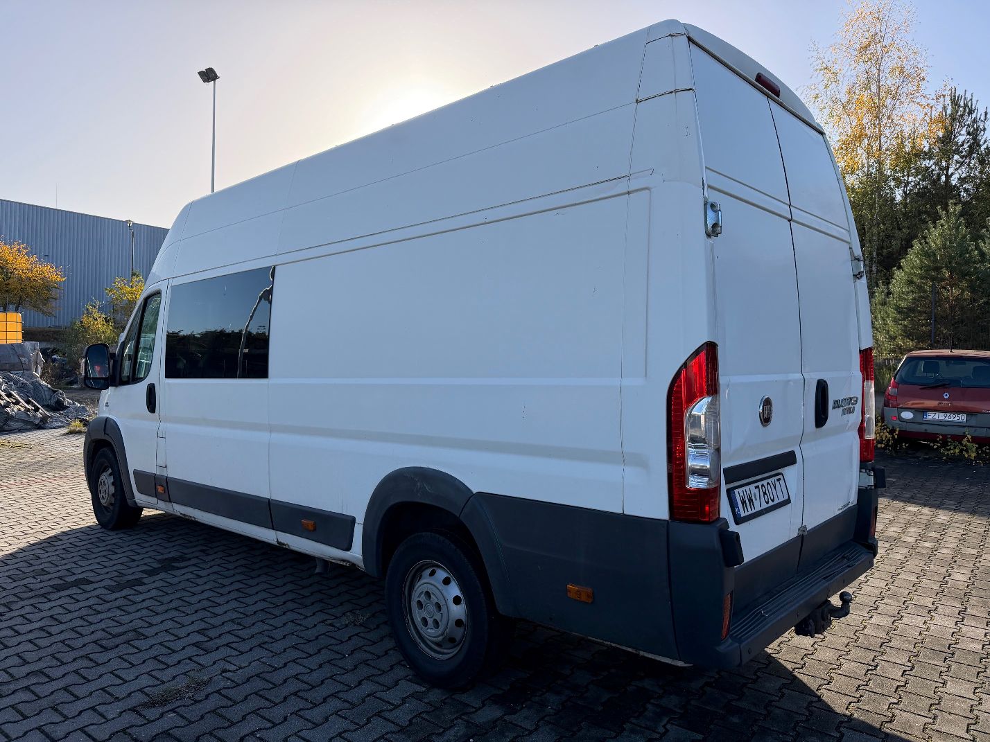 Biały Fiat Ducato, ujęcie lewego boku i tyłu pojazdu.