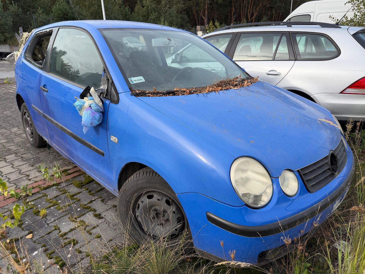 Niebieski Volkswagen Polo, widok z przodu prawego boku, połamane zewnętrzne prawe lusterko.