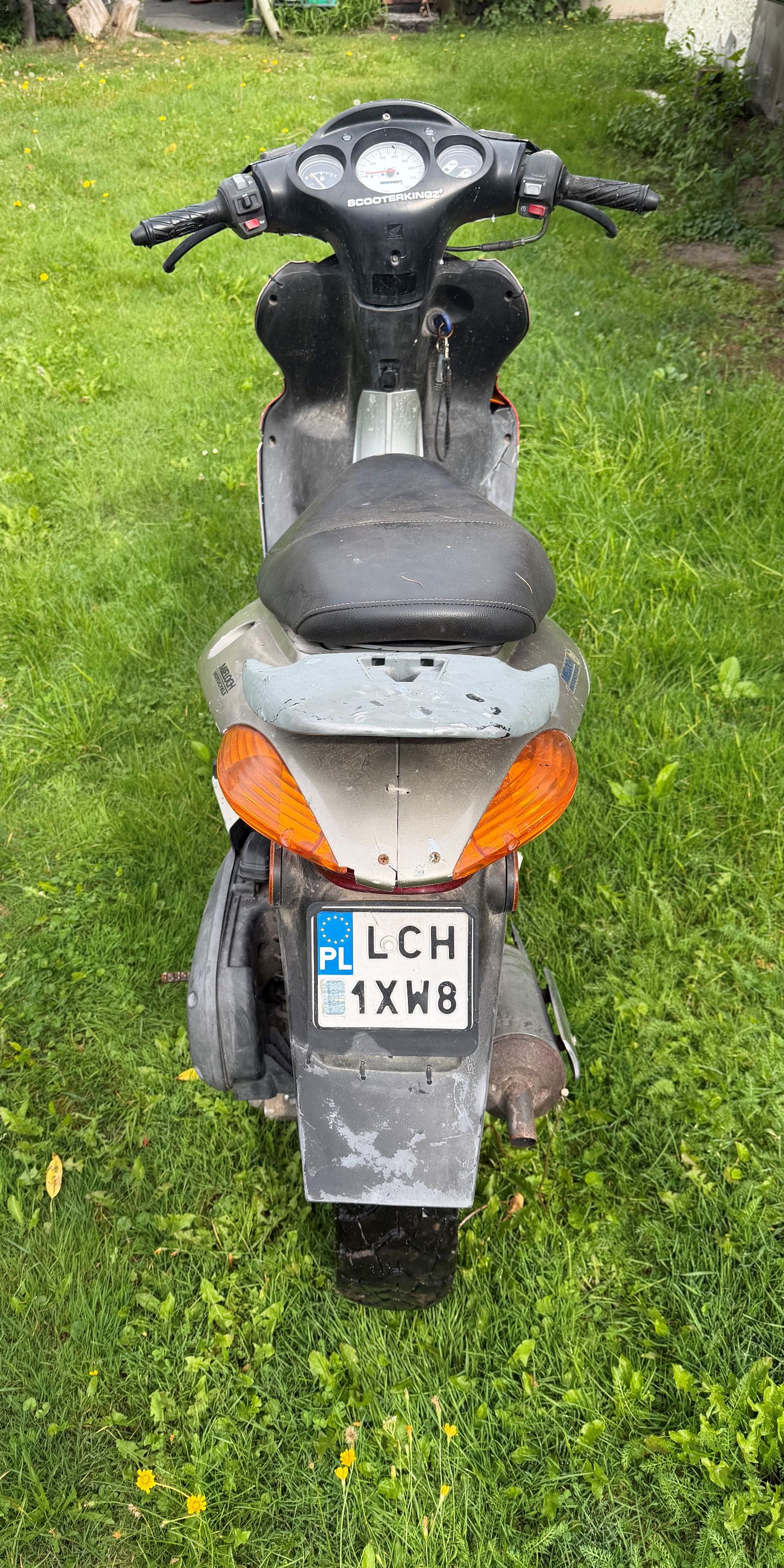 Skuter w kolorze czerwono srebrnym. Widok od tyłu motoroweru.