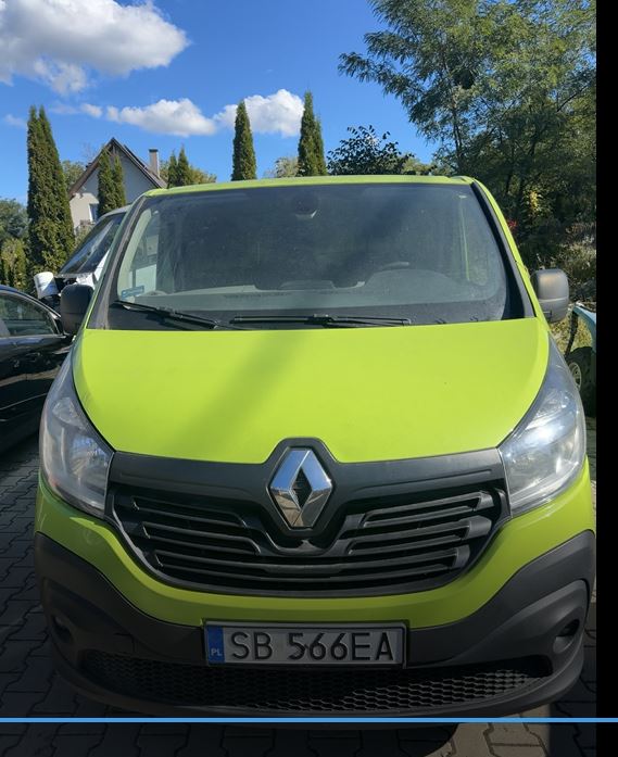 Przód samochodu w jaskrawym kolorze, grillem ,logo oraz tablicą rejestracyjną.