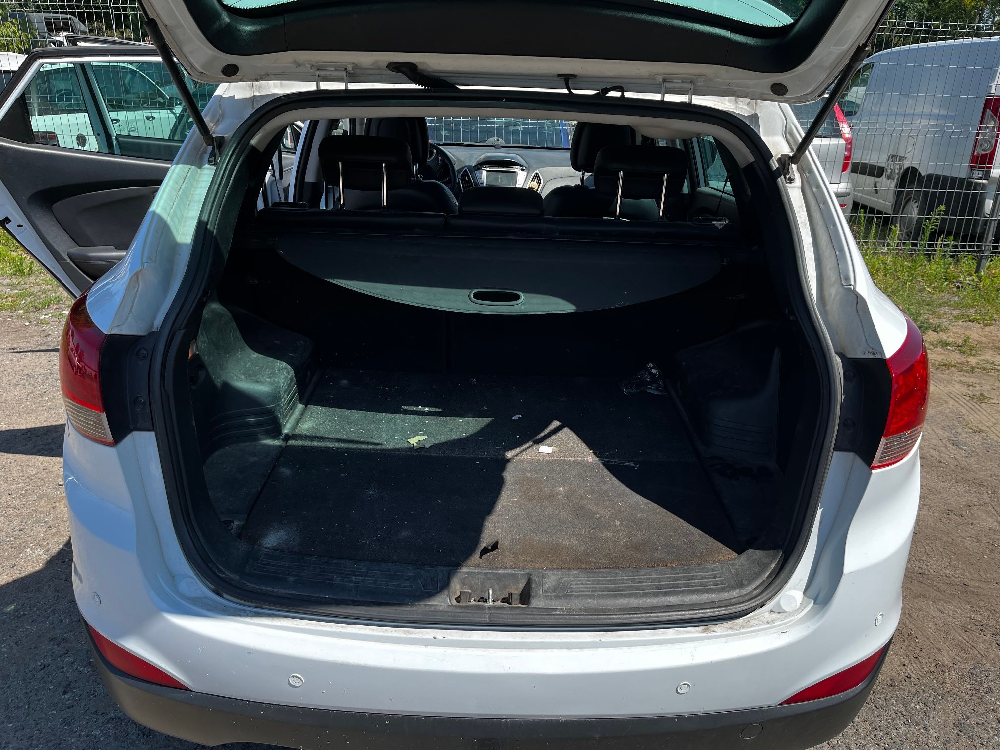 Otwarty bagażnik białego Hyundai Tuscon