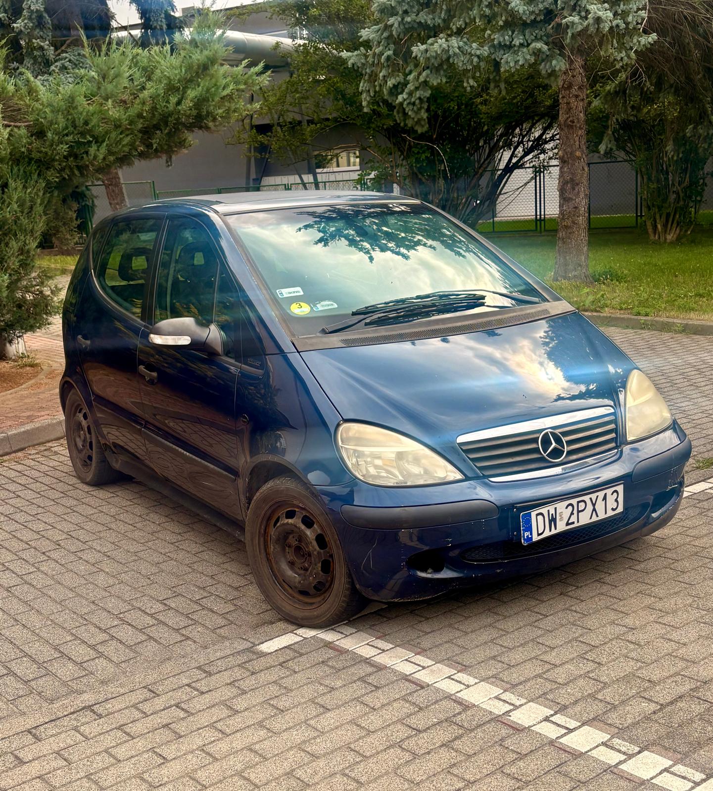 Mercedes-Benz w kolorze granatowym, widok z boku, z widoczną tablicą rejestracyjną.