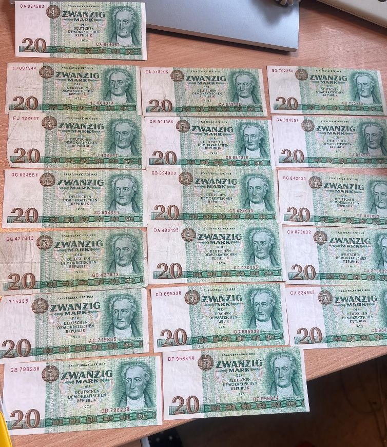 Kolekcja osiemnastu banknotów o nominale 20 marek NRD z 1975 roku ułożonych w rzędach.