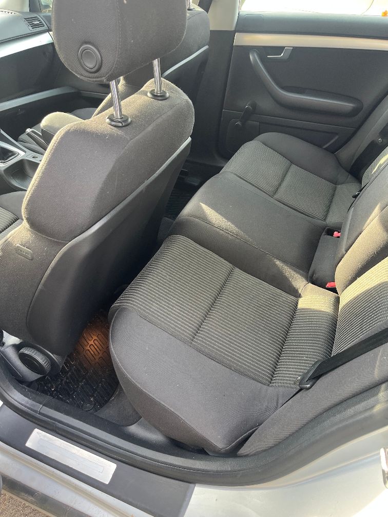 Widok na tylne siedzenia Audi A4 B7 z ciemną, materiałową tapicerką w drobne paski.