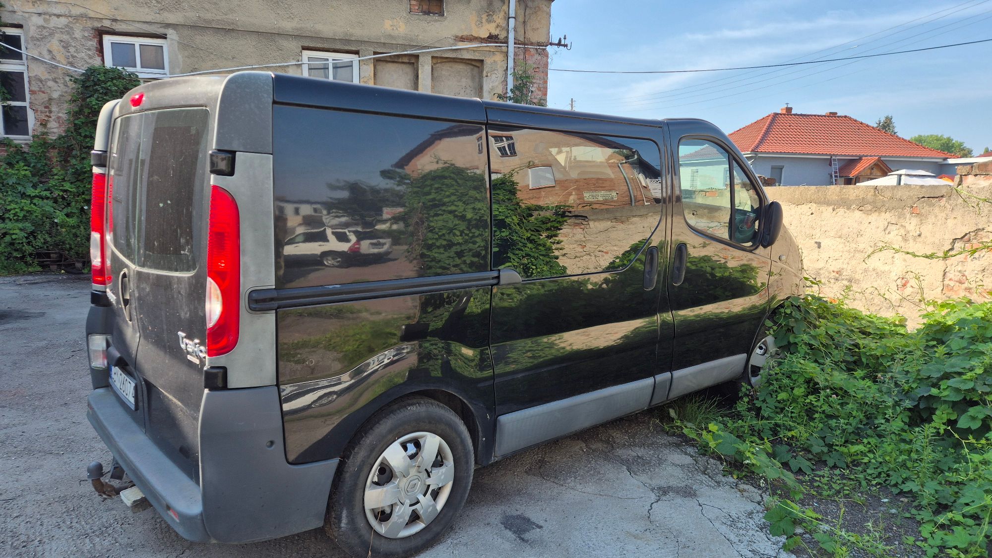 Prawa strona nadwozia Renault Trafic koloru czarnego. Felgi stalowe, kołpaki plastikowe z logo producenta.