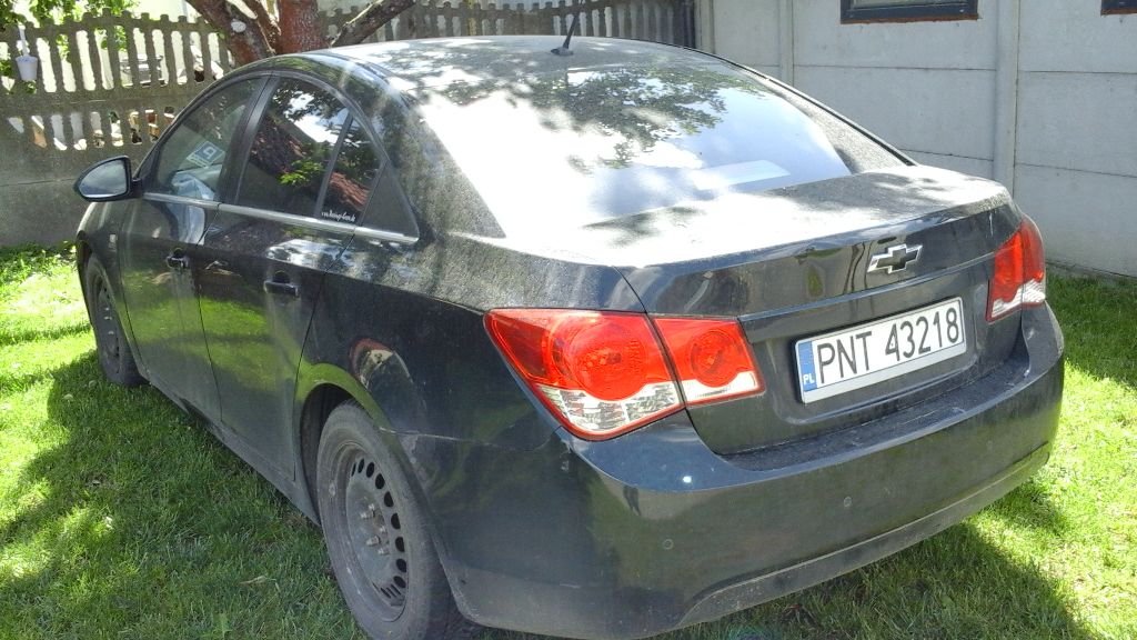 Czarny sedan marki Chevrolet Cruze, widoczny od tyłu i z lewego boku.