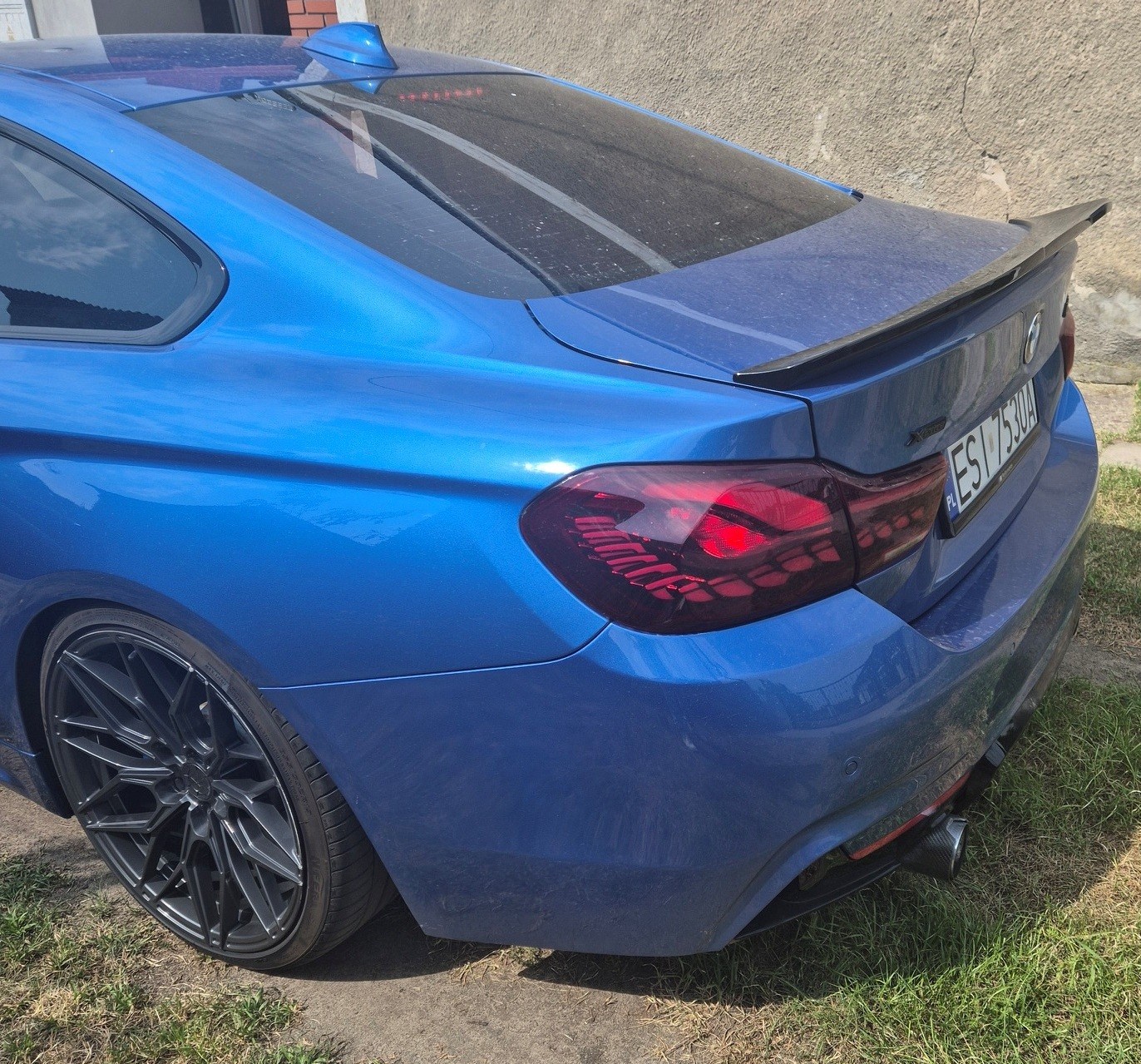Niebieskie BMW z polską tablicą rejestracyjną, zdjęcie tył lewego profilu.