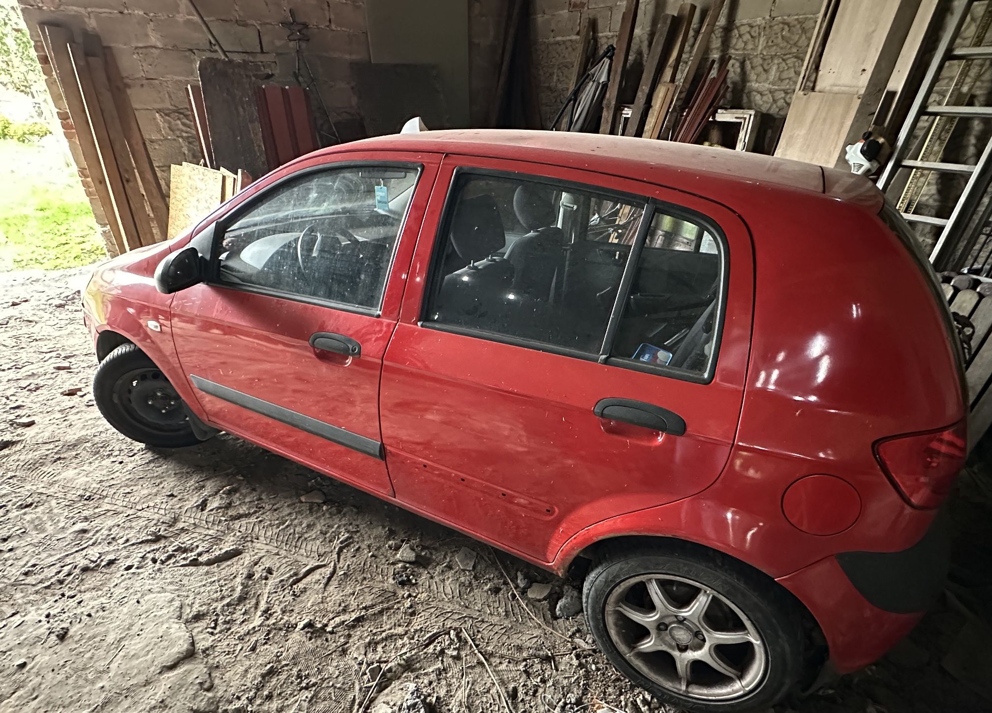 Widok na lewy bok czerwonego pięciodrzwiowego auta Hyundai Getz.