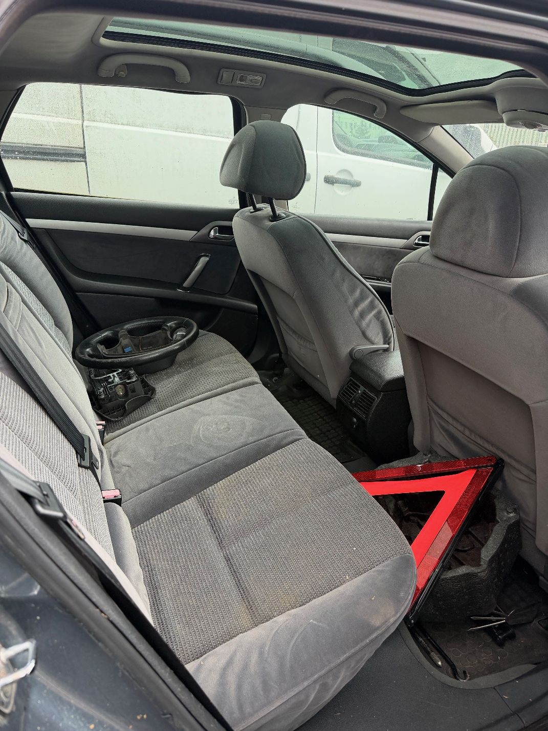 Szary Peugeot 407 SW, szara tylna kanapa z widocznymi śladami zużycia i zabrudzeniami oraz czarnymi plastikowymi elementami.