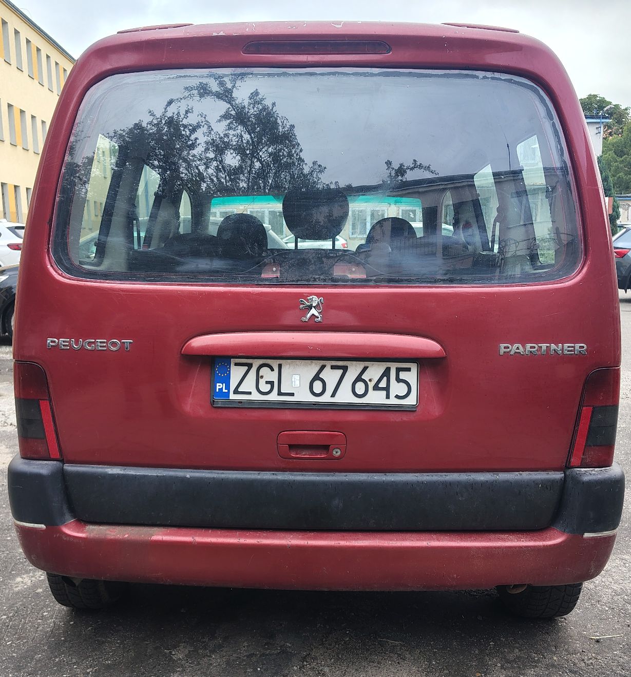 Widok z tyłu, brak wgnieceń, widoczne ślady korozji na zderzaku, pojazd stoi na kołach.