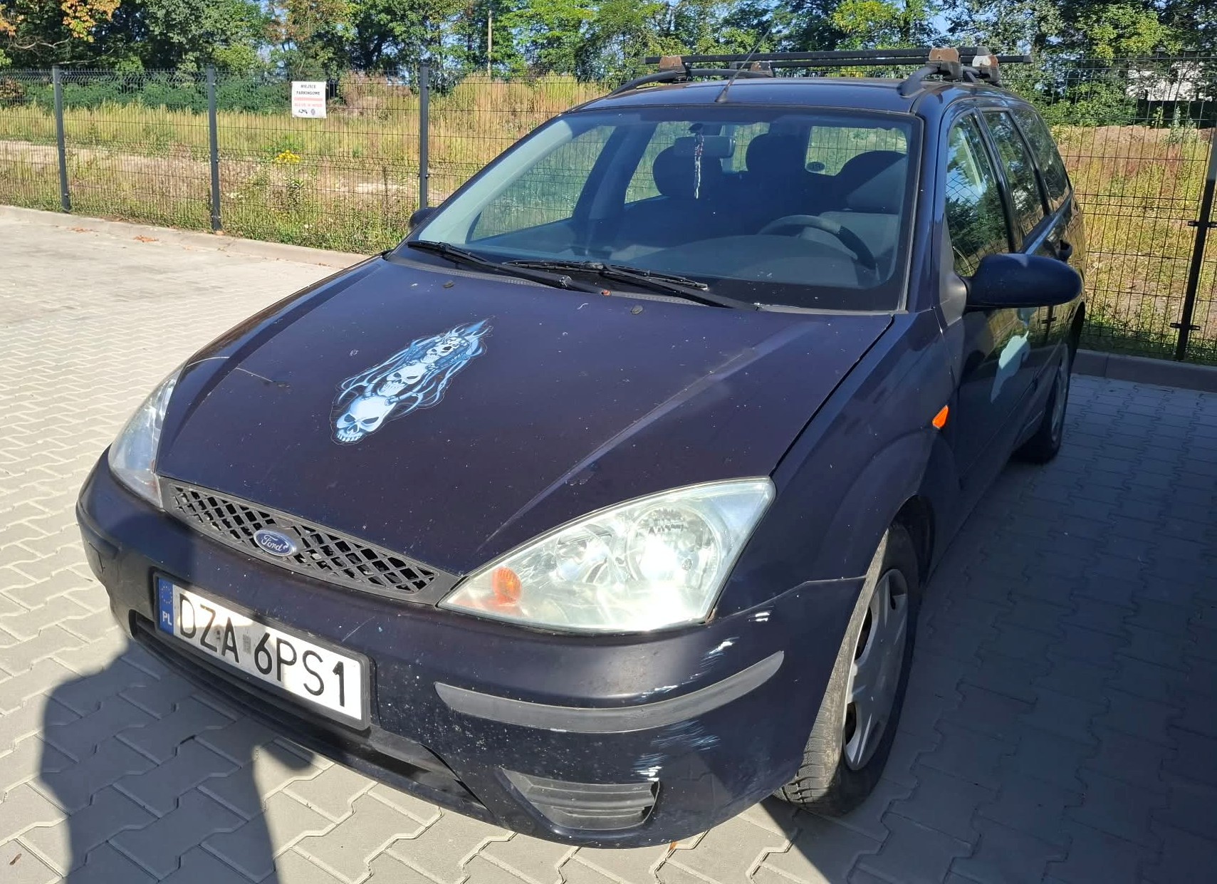 Widok przodu oraz lewego boku granatowego samochodu ford focus.