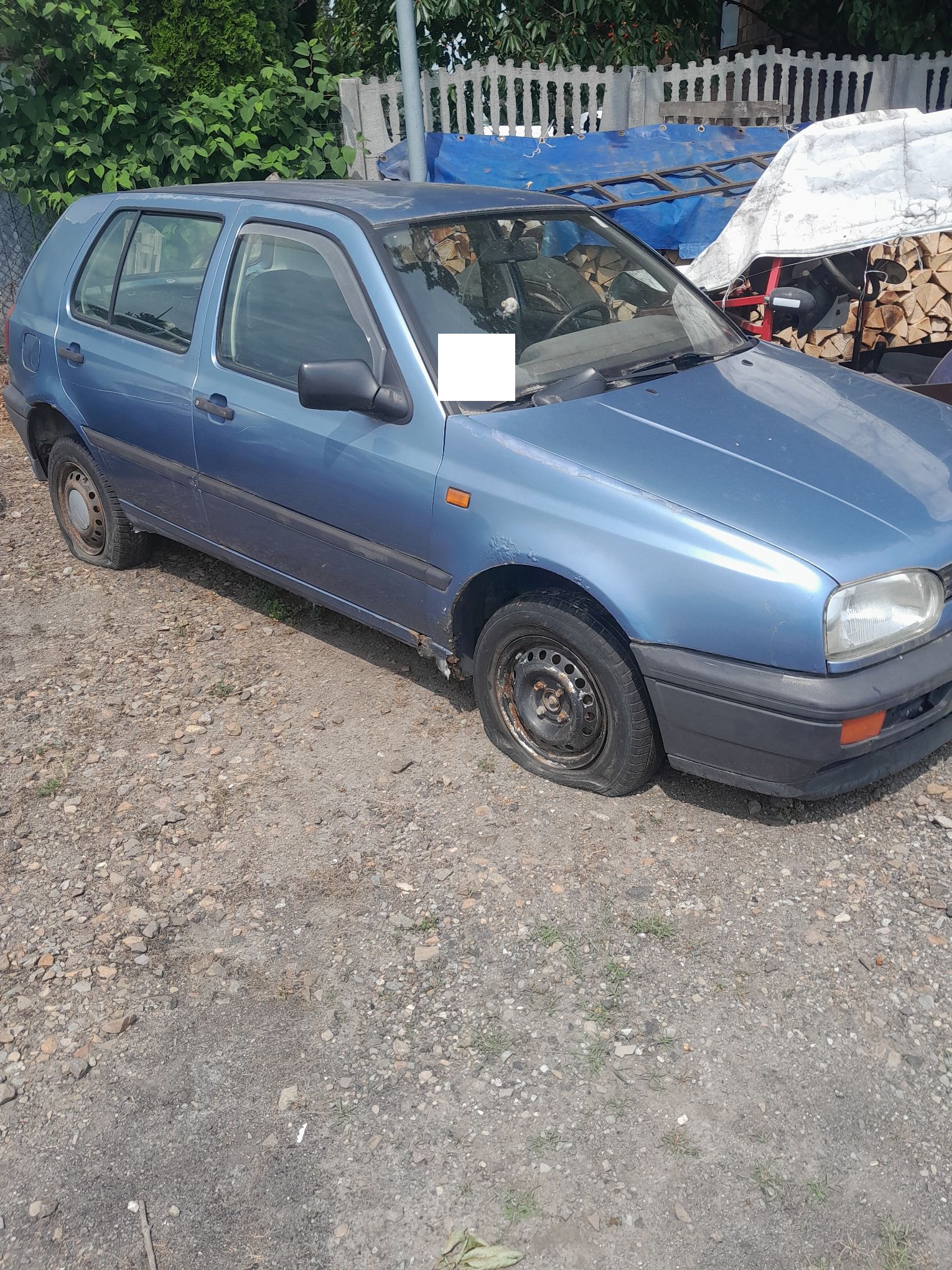 Niebieski Volkswagen Golf, widziany od prawej strony pojazdu , brak powietrza w kołach, korozja w progu