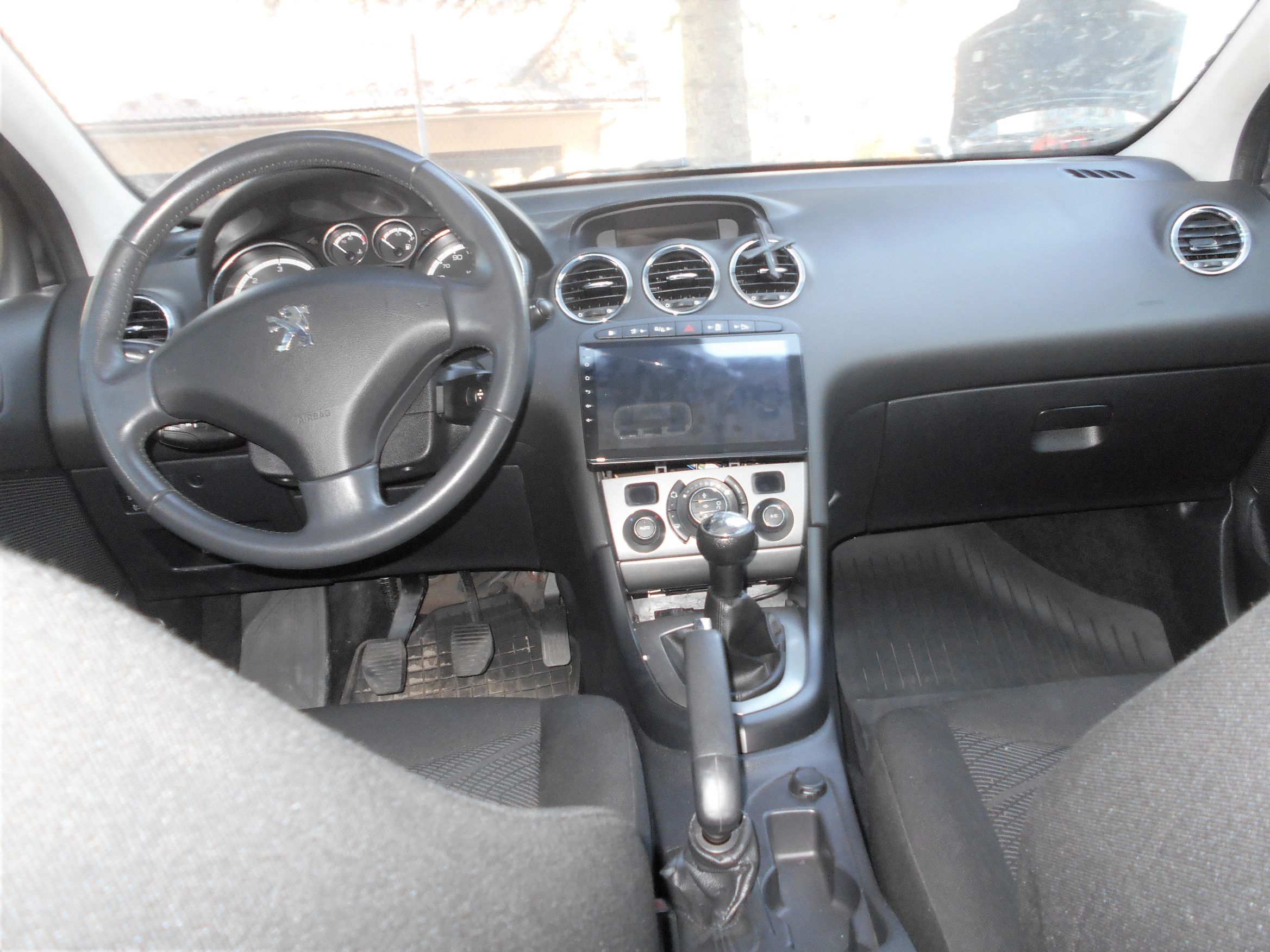 Wnętrze samochodu Peugeot z manualną skrzynią biegów.
