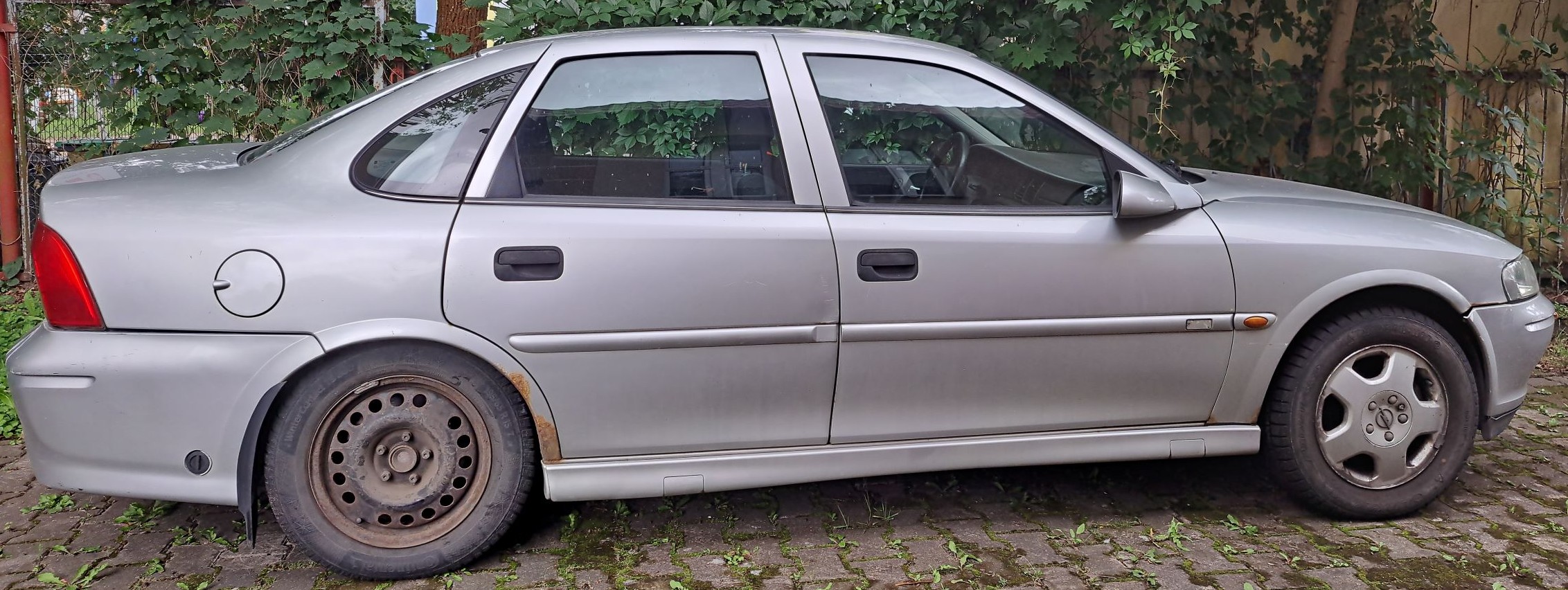prawa strona samochodu osobowego Opel Vectra brak widocznych uszkodzeń ślady korozji w zderzaku zamontowany wlew do paliwa LPG