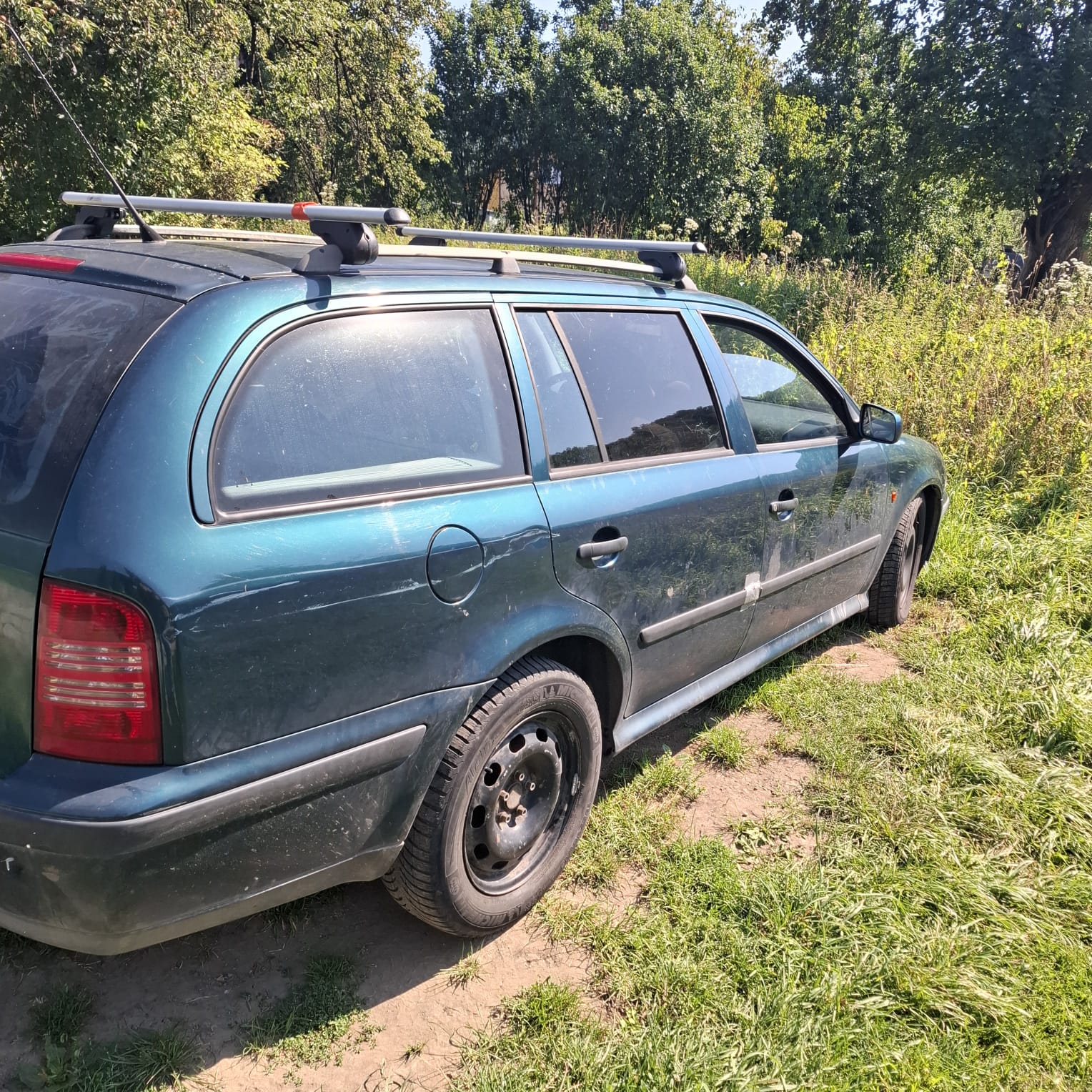 Zarysowany i zabrudzony prawy bok zielonego samochodu osobowego Skoda Octavia.