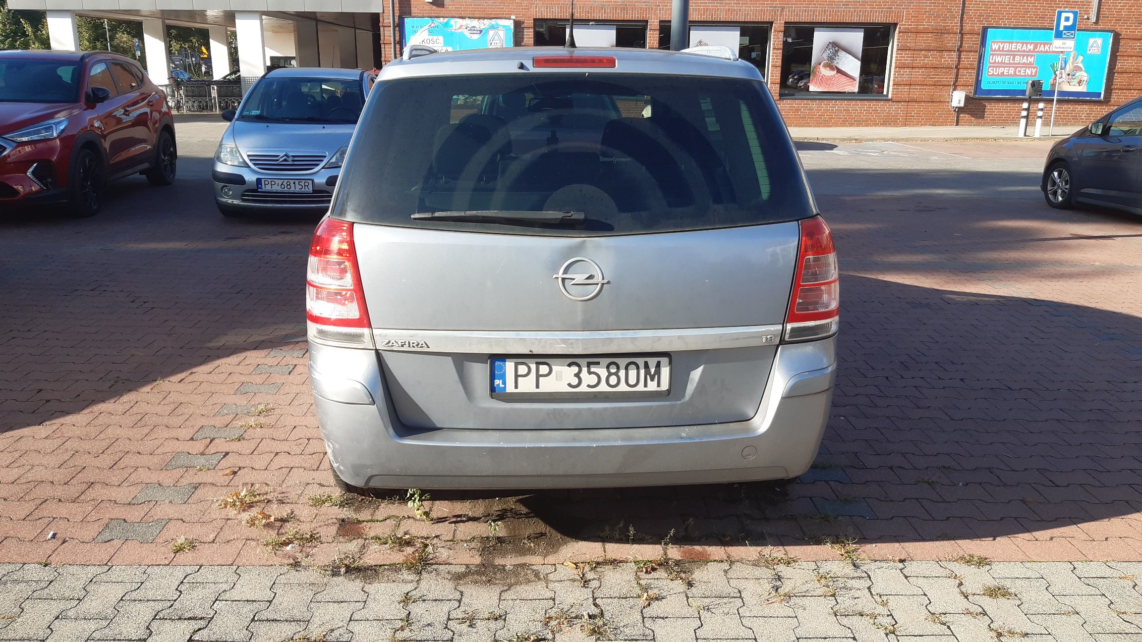 Srebrny samochód osobowy Opel Zafira widok z tyłu