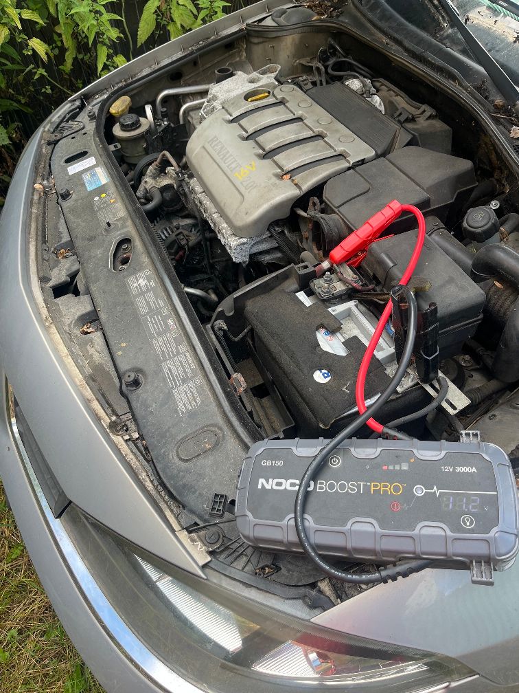 Widok z góry na otwartą komorę czterocylindrowego silnika benzynowego srebrnego samochodu Renault Laguna.