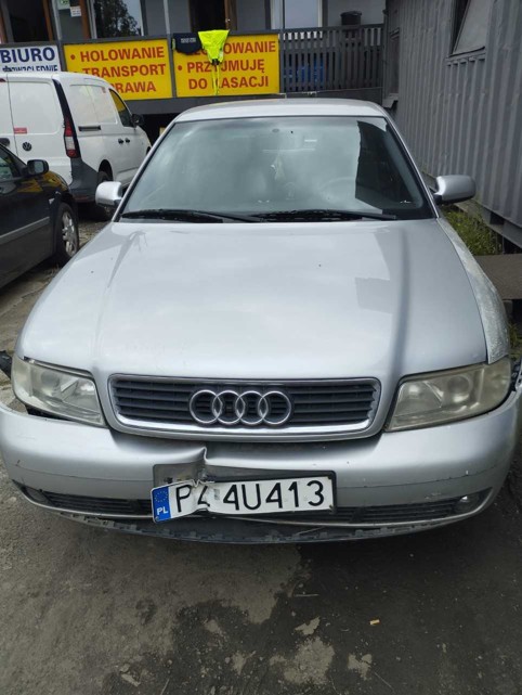 Srebrne Audi A4, uszkodzony przedni zderzak. Prawy reflektor prawidłowo spasowany, przy lewym widoczna szczelina