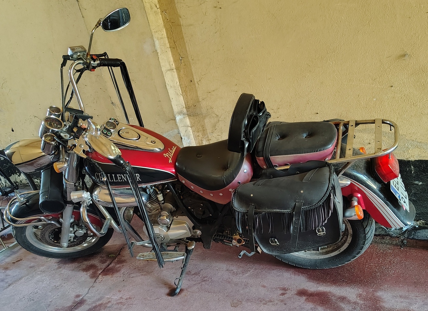 Motocykl marki chińskiej. Turystyczny. W kolorze czerwono-czarnym. Posiada sakwy zamontowane po obu stronach tylnego koła.