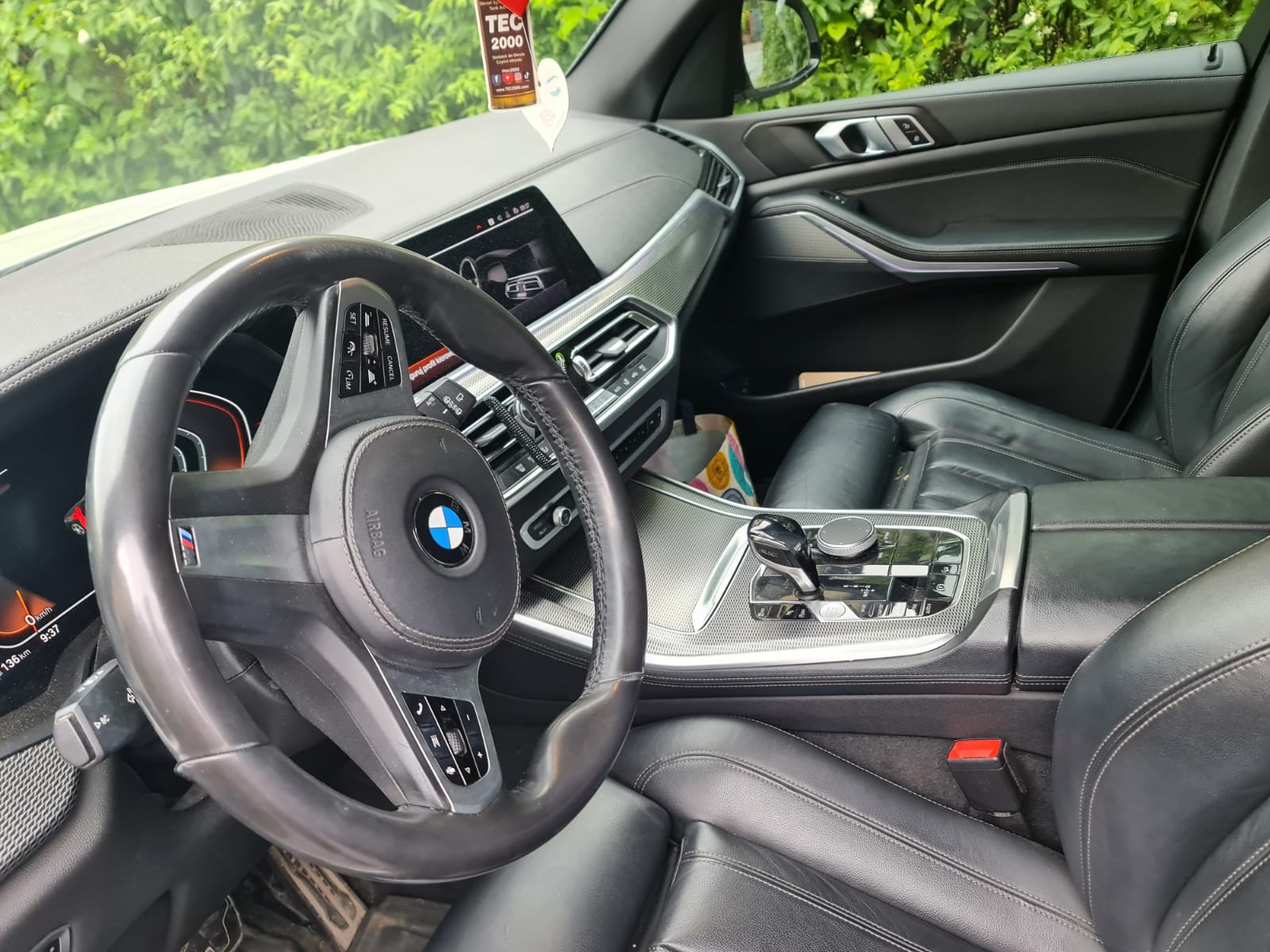 Wnętrze samochodu BMW z czarną skórzaną tapicerką, nowoczesną konsolą centralną i ekranem dotykowym na desce rozdzielczej.