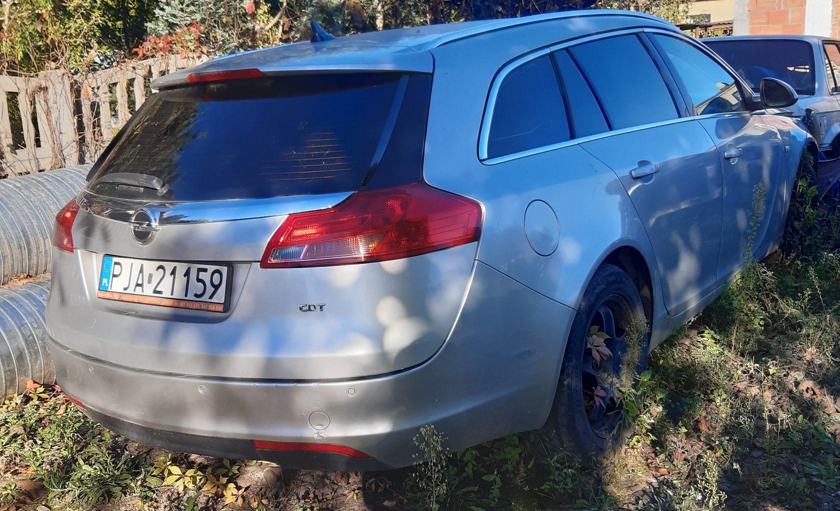 Srebrny Opel Insignia (kombi) widoczny od tyłu pod kątem, z tablicą PJA 21159