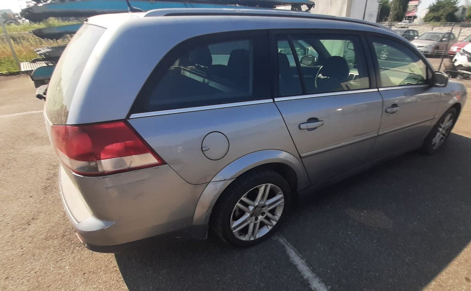 Prawy bok samochodu Opel Vectra, kolor srebrny. Karoseria lekko uszkodzona, widoczne wgniecenie obok tylnej lampy.