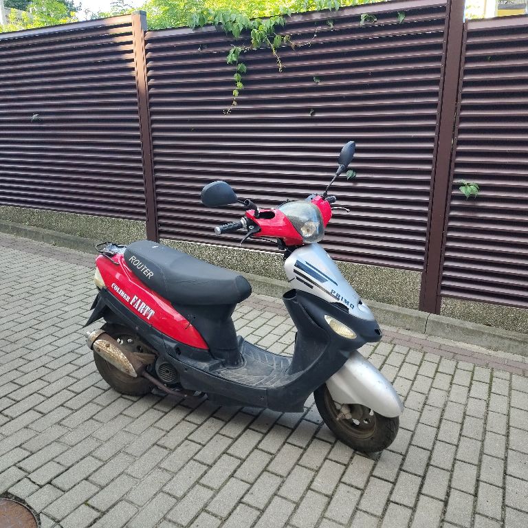 Motorower koloru czarno-czerwonego. Korozja na tłumiku i rurze wydechowej.