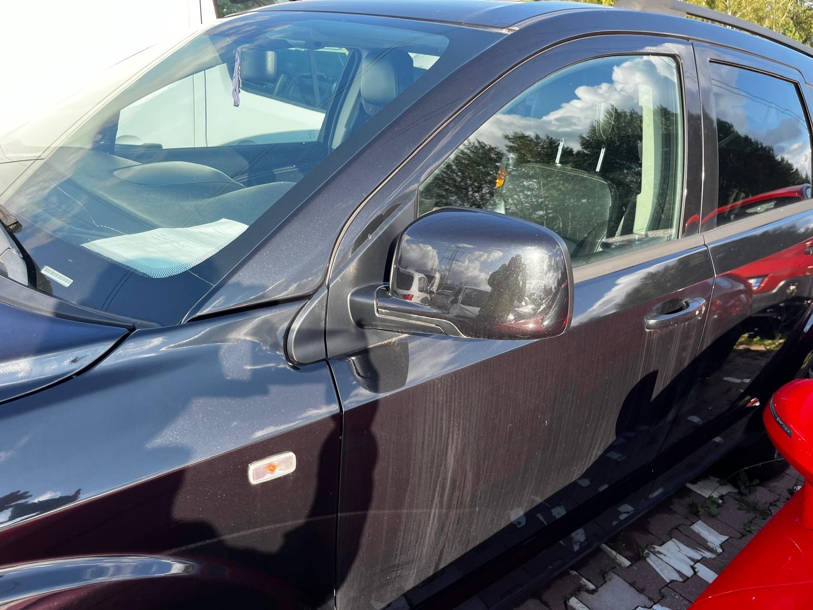 Na zdjęciu widoczny jest Fiat Freemont. Charakteryzuje się czarnym lakierem, ciemną atrapą chłodnicy oraz logo marki FIAT