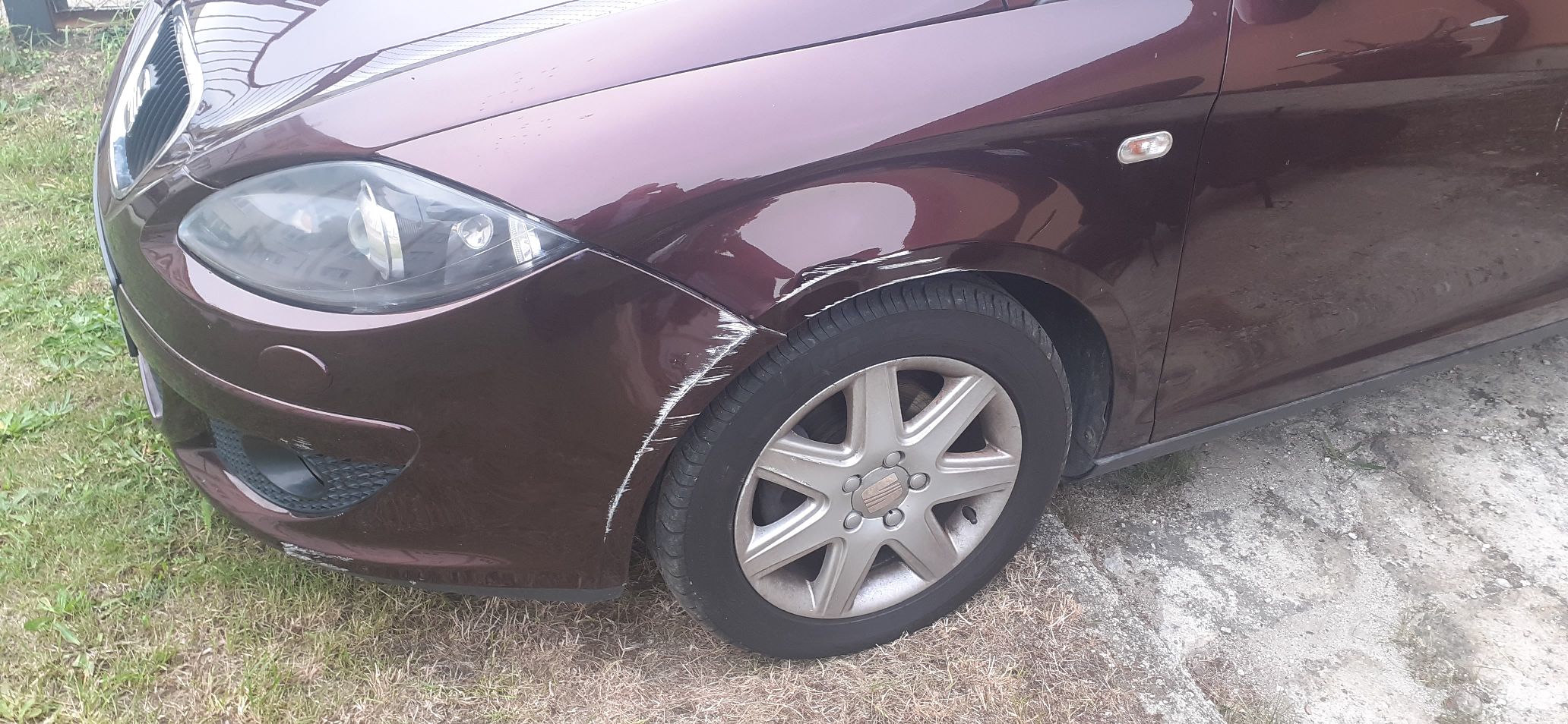 Prawy bok samochodu SEAT ALTEA XL. Uszkodzenie błotnika oraz zderzaka. Widoczne rysy i przetarcia lakieru.