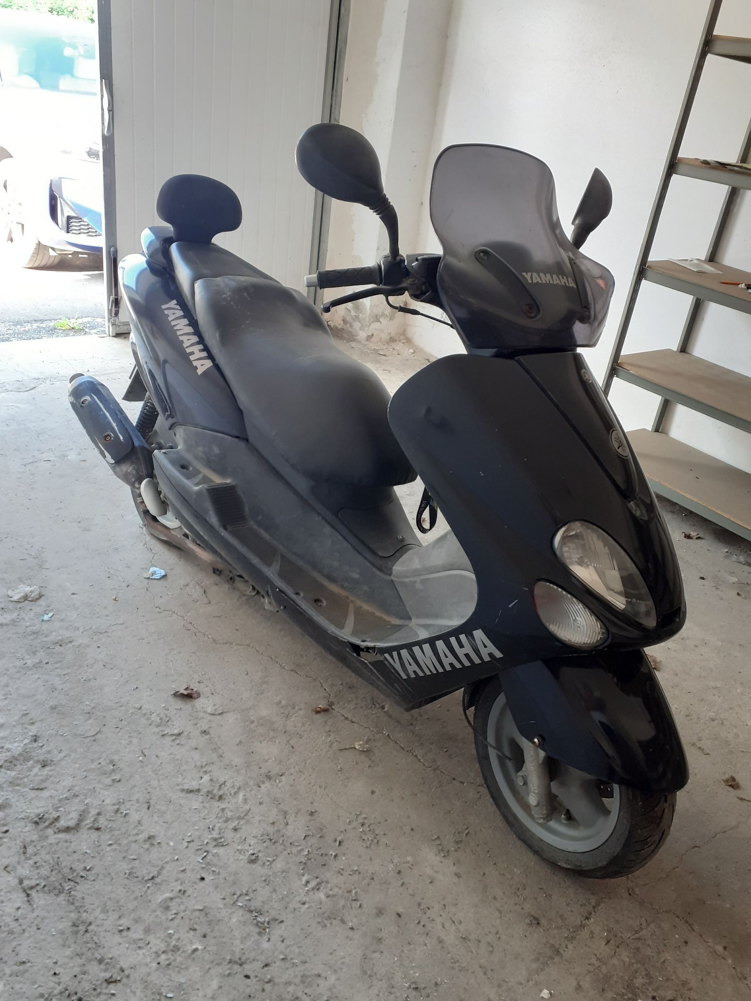 Czarny motorower Yamaha Majesty z przednią szybą i profilowaną kanapą z oparciem.