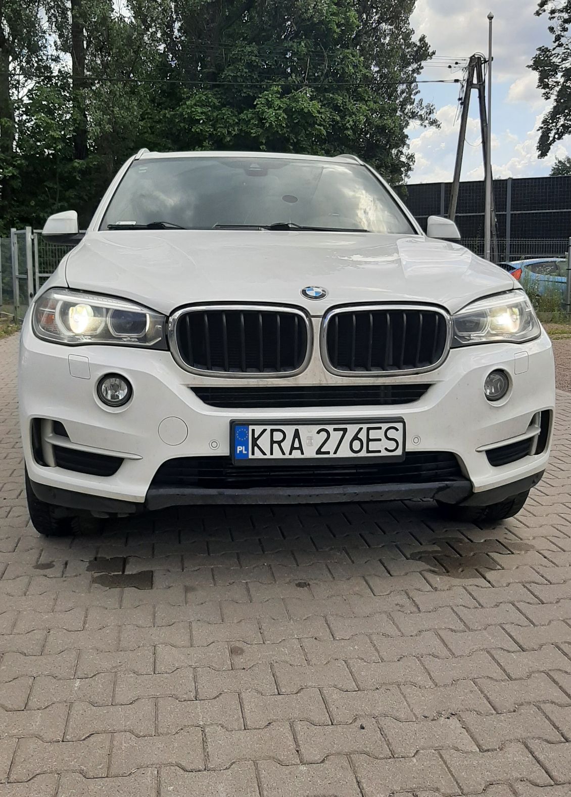 Biały SUW marki BMW zaparkowany na podjeździe