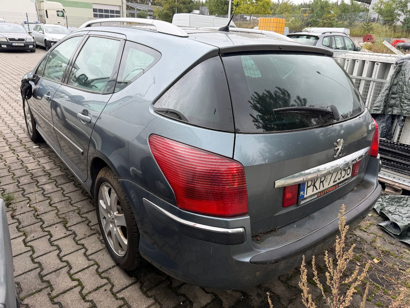 Szary Peugeot 407 SW, widok z tytułu lewego boku, srebrne relingi dachowe oraz chromowana listwa na klapie bagażnika.